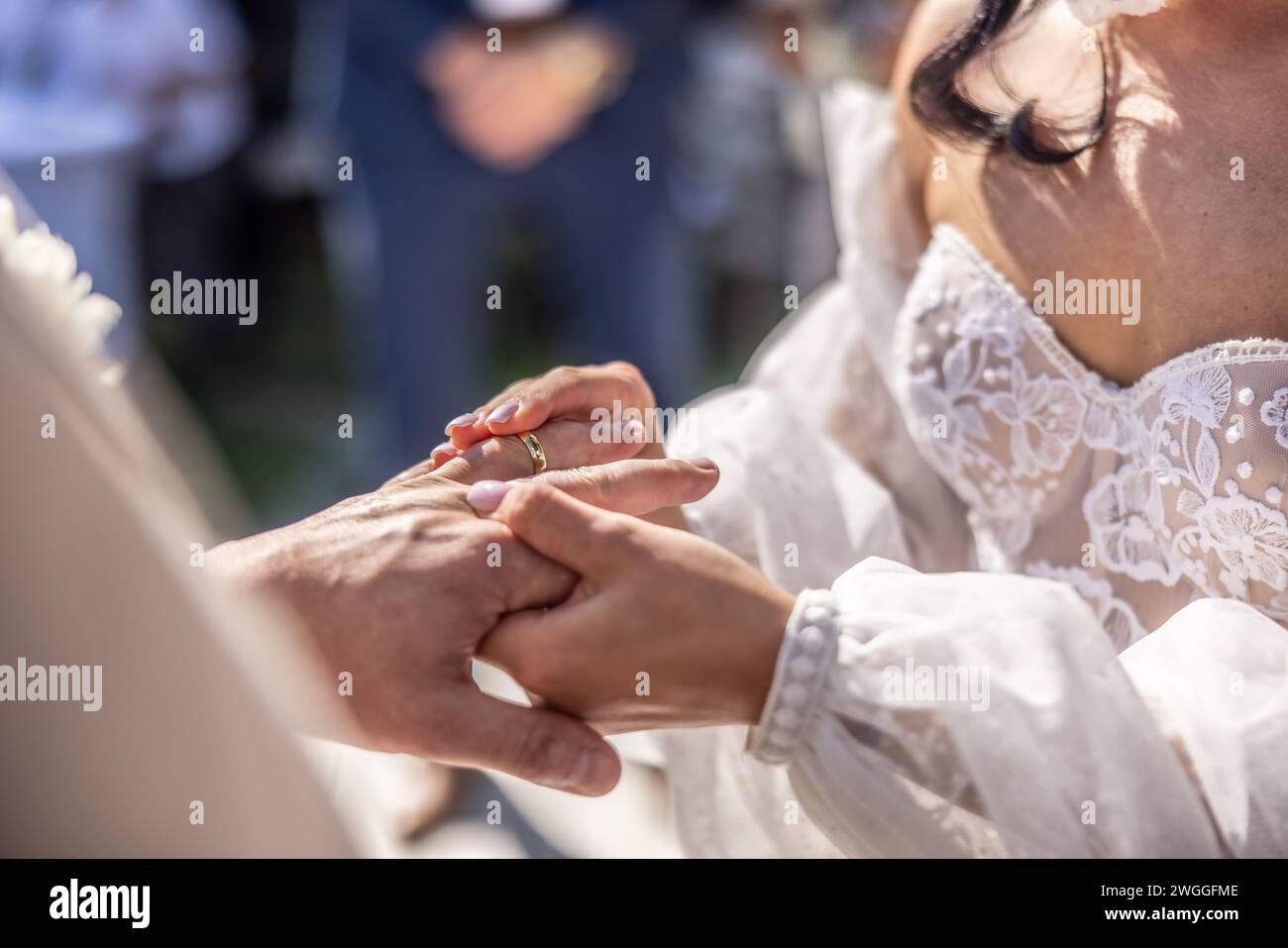 Wedding rings exchange with bride putting a ring on her future husband's finger. Stock Photo