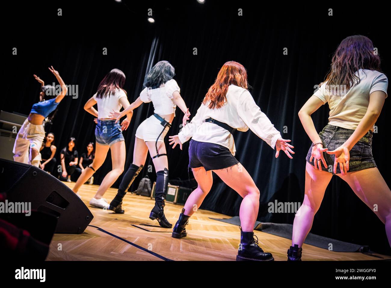 Group of diverse women in stylish outfits and black boots performing on stage Stock Photo