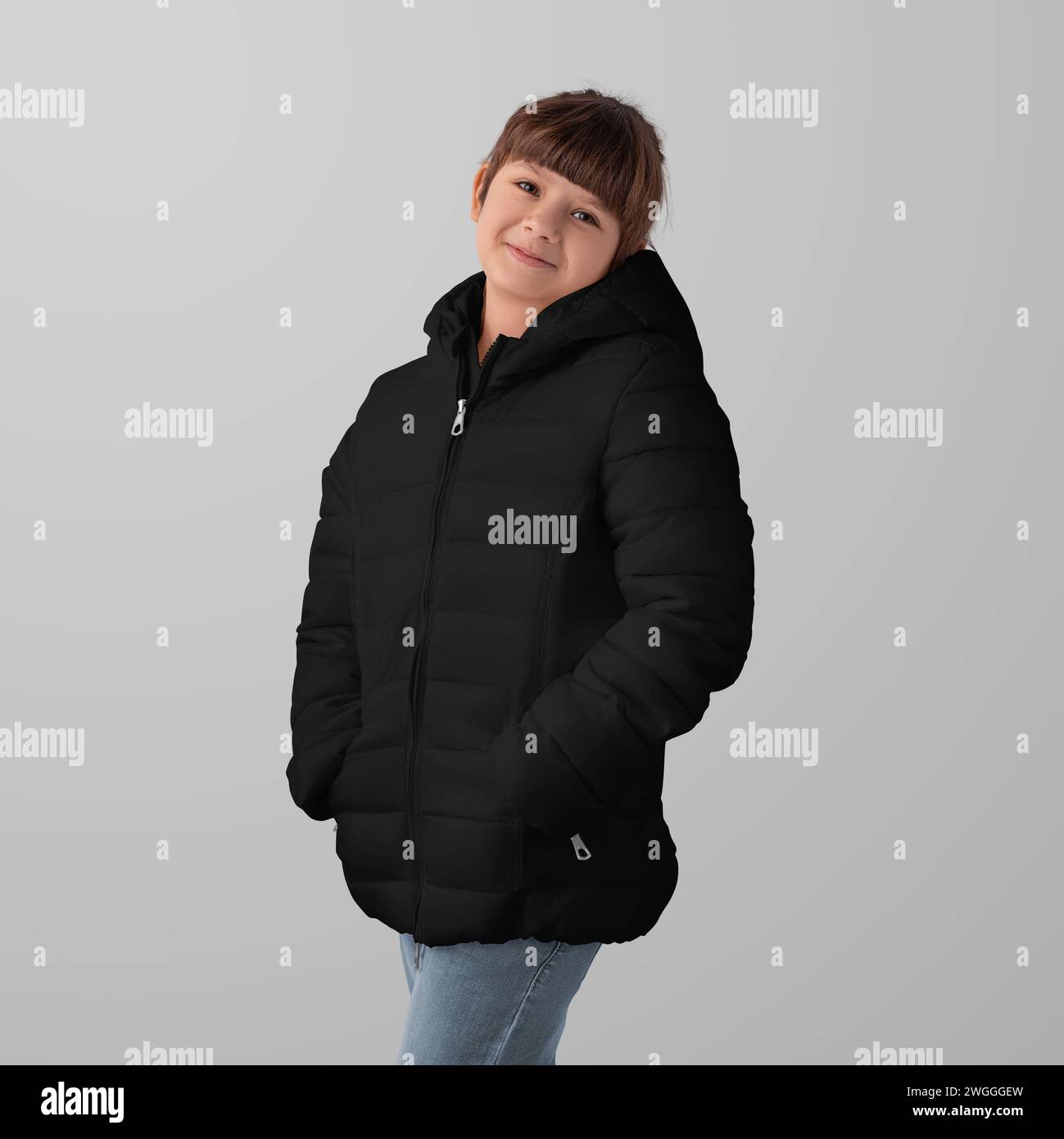 Mockup of a black winter puffer jacket on a child, garment zippers up, hands in pockets, front view, space for design, branding. Template fashionable Stock Photo