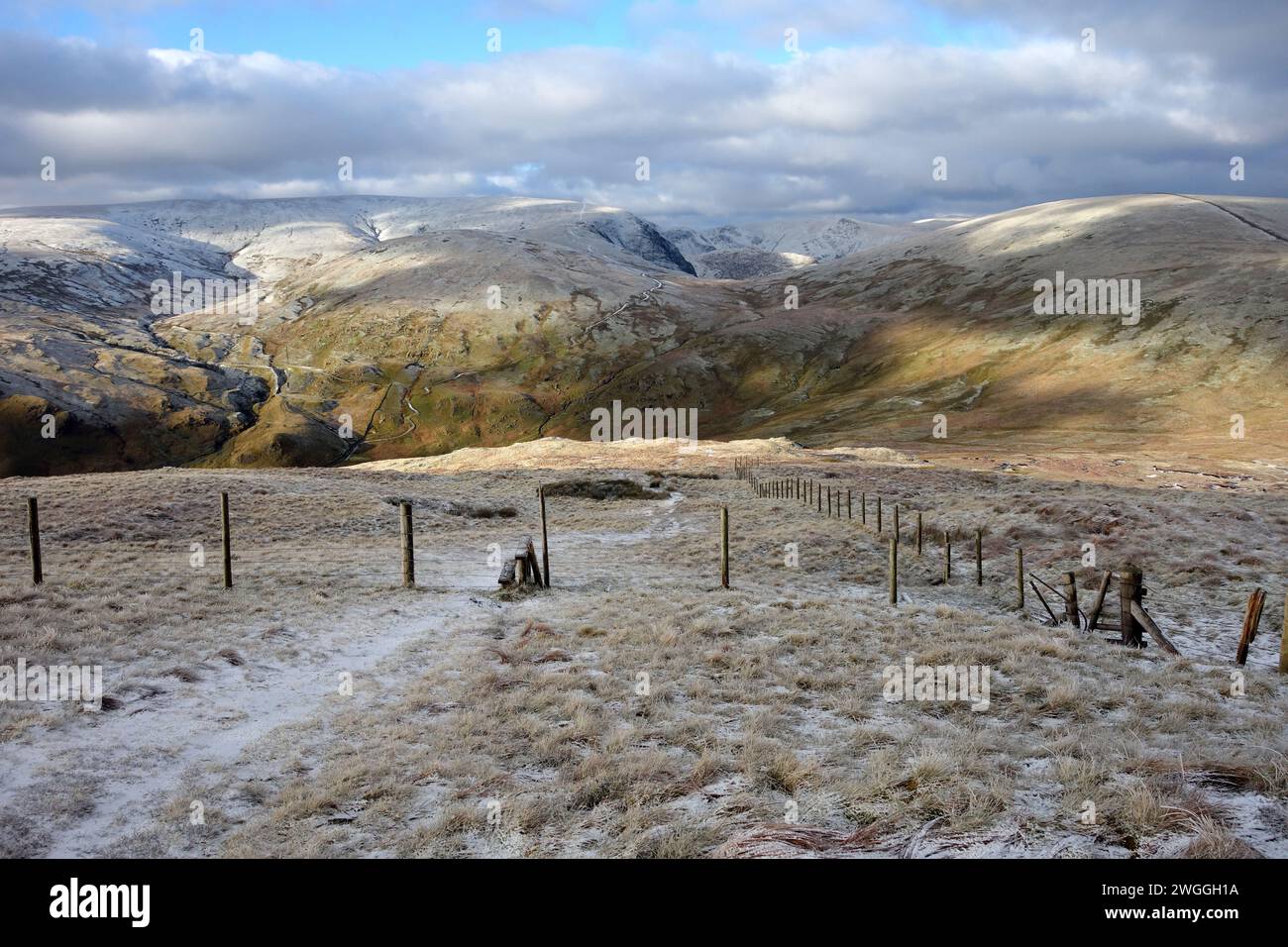 The 'High Street' Mountain Range and Wooden Stile in a Wire Fence  near the Summit of 'Tarn Crag' Lake District National Park, Cumbria, England, UK Stock Photo