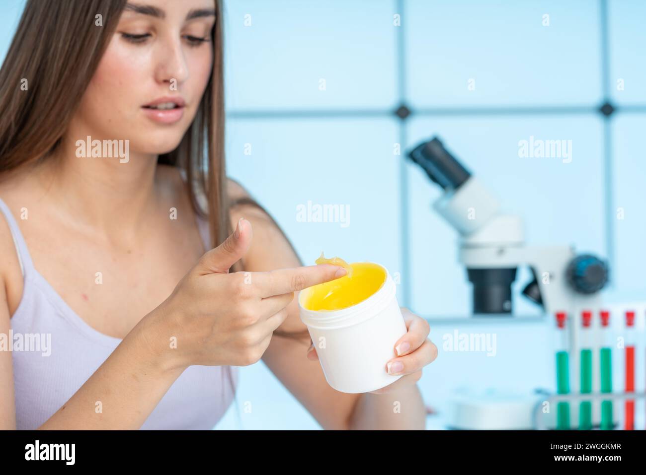 young woman uses medical ointment from a plastic jar Stock Photo