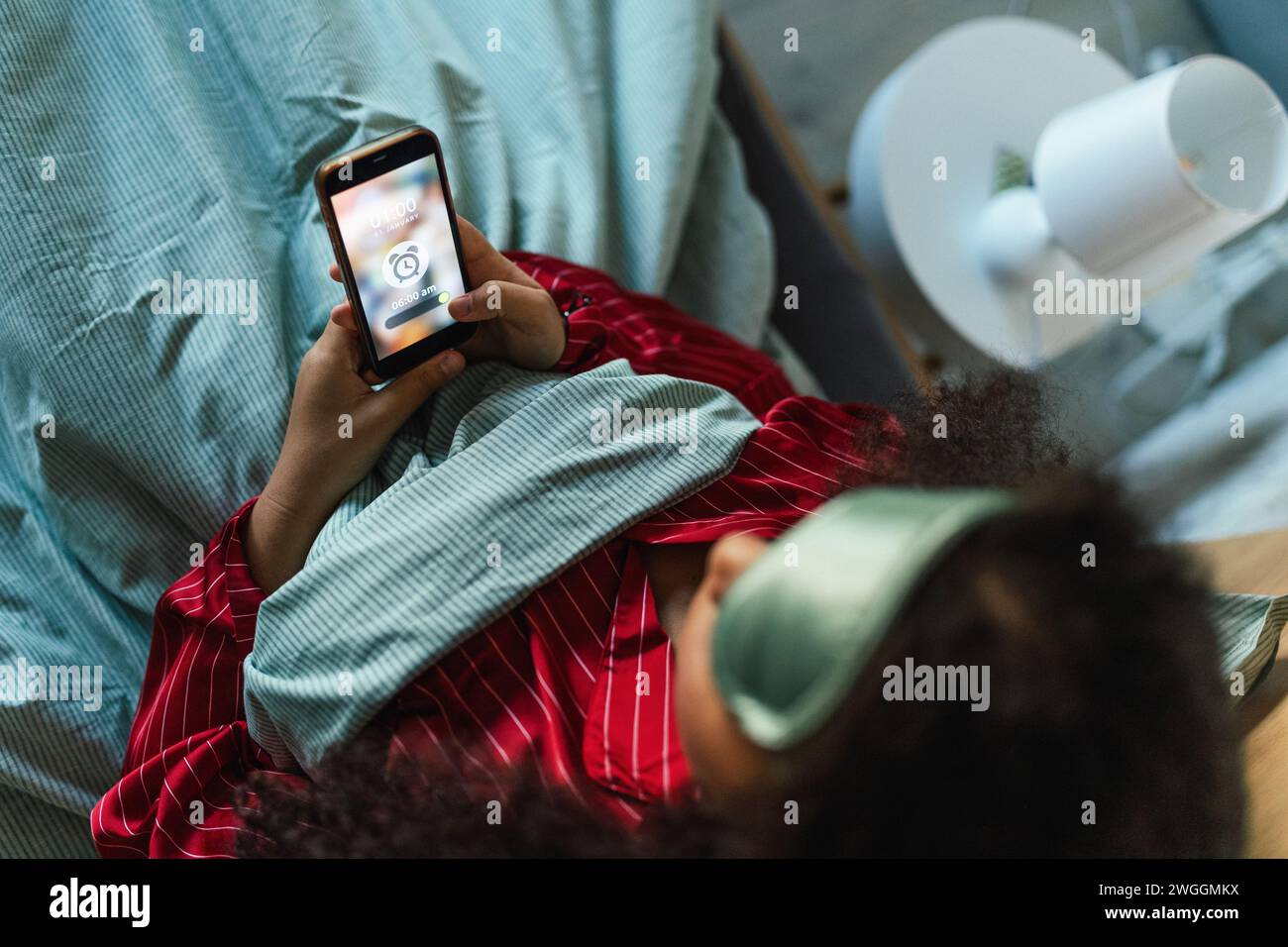 Woman setting alarm before going to sleep. Concept of sleep routine. Insomnia a sleep problems among adults. Stock Photo