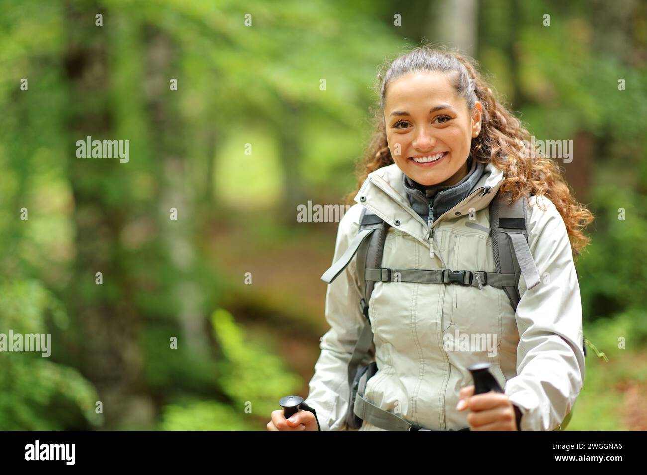 Happy hiker trekking looking at you in a forest Stock Photo