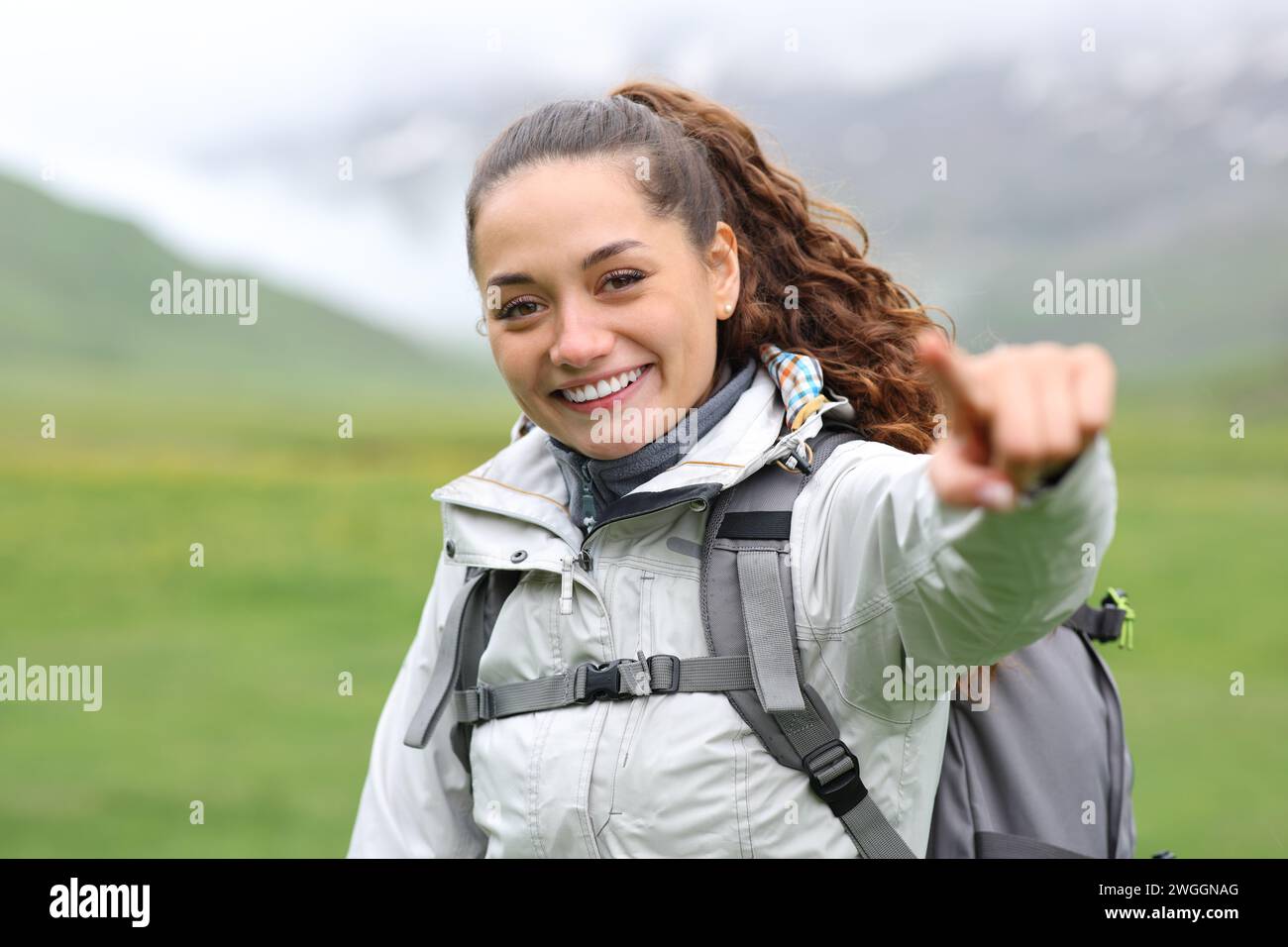 Happy hiker pointing at camera in the mountain Stock Photo