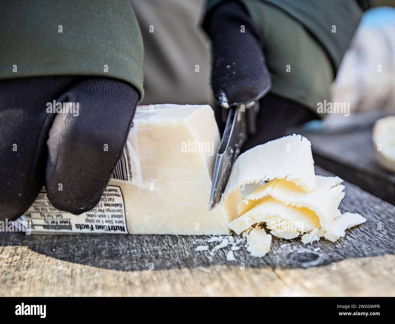 Close up of person cutting cheese, Allagash Wilderness Waterway, Maine, USA Stock Photo
