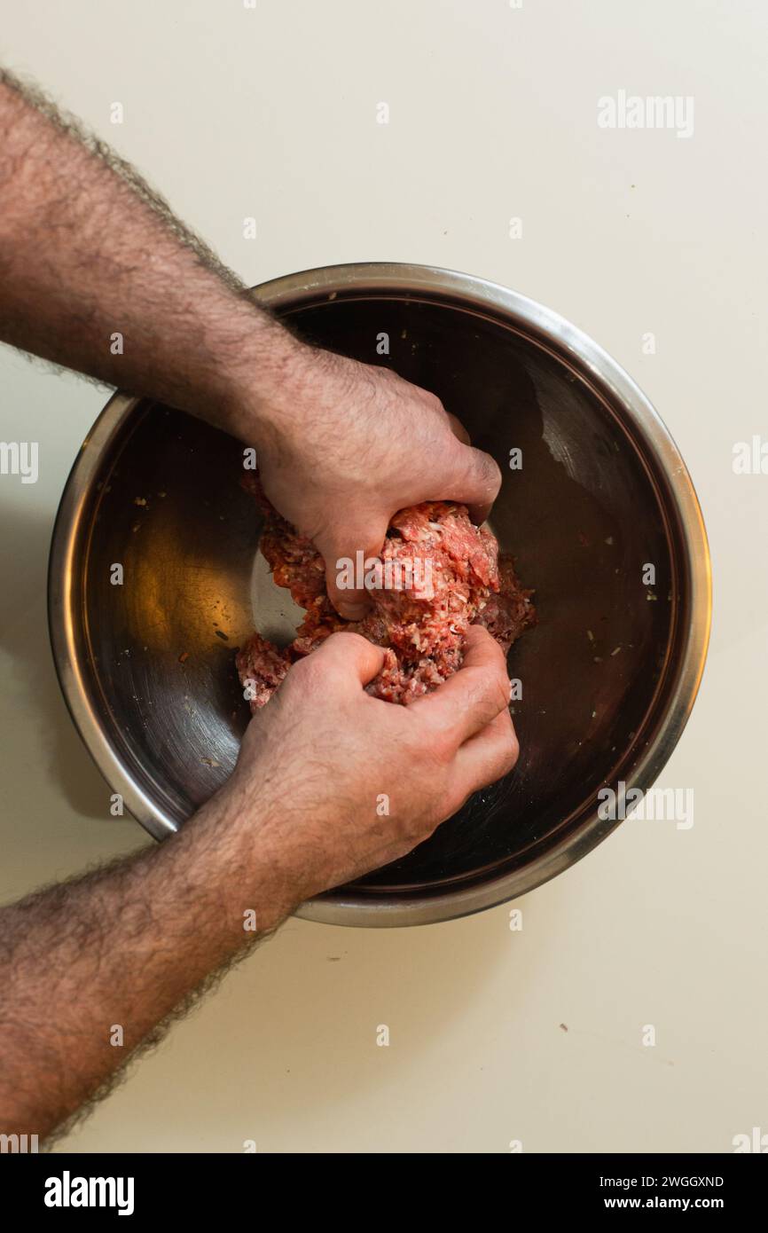 Man mixing ground meat in metal bowl Stock Photo