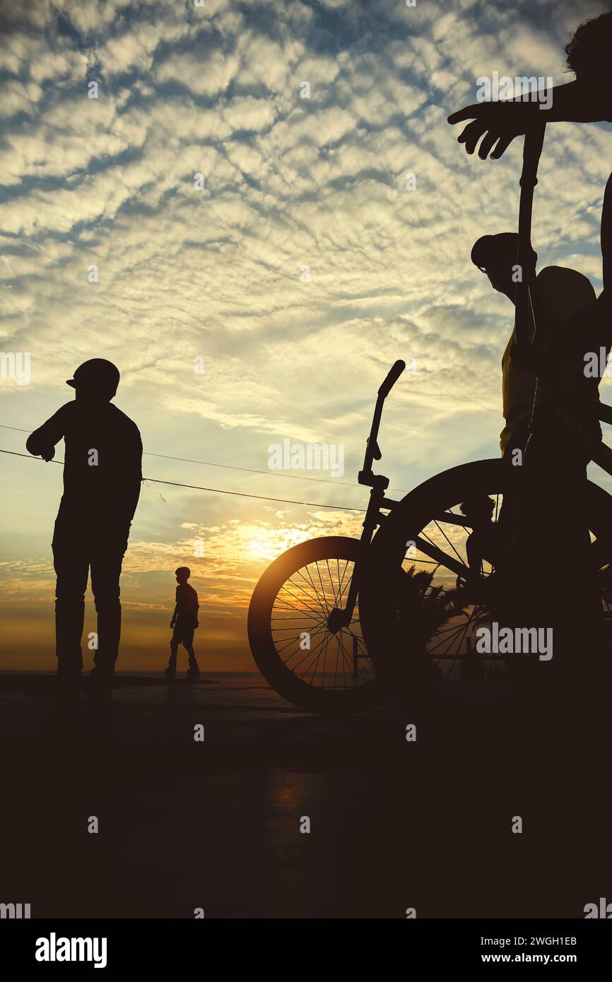 Skateboarding and BMX bike Silhouette Extreme Skatepark Images Orange Sunlight Youth Culture Enjoy Sports Vacation Skateboard Stock Photo