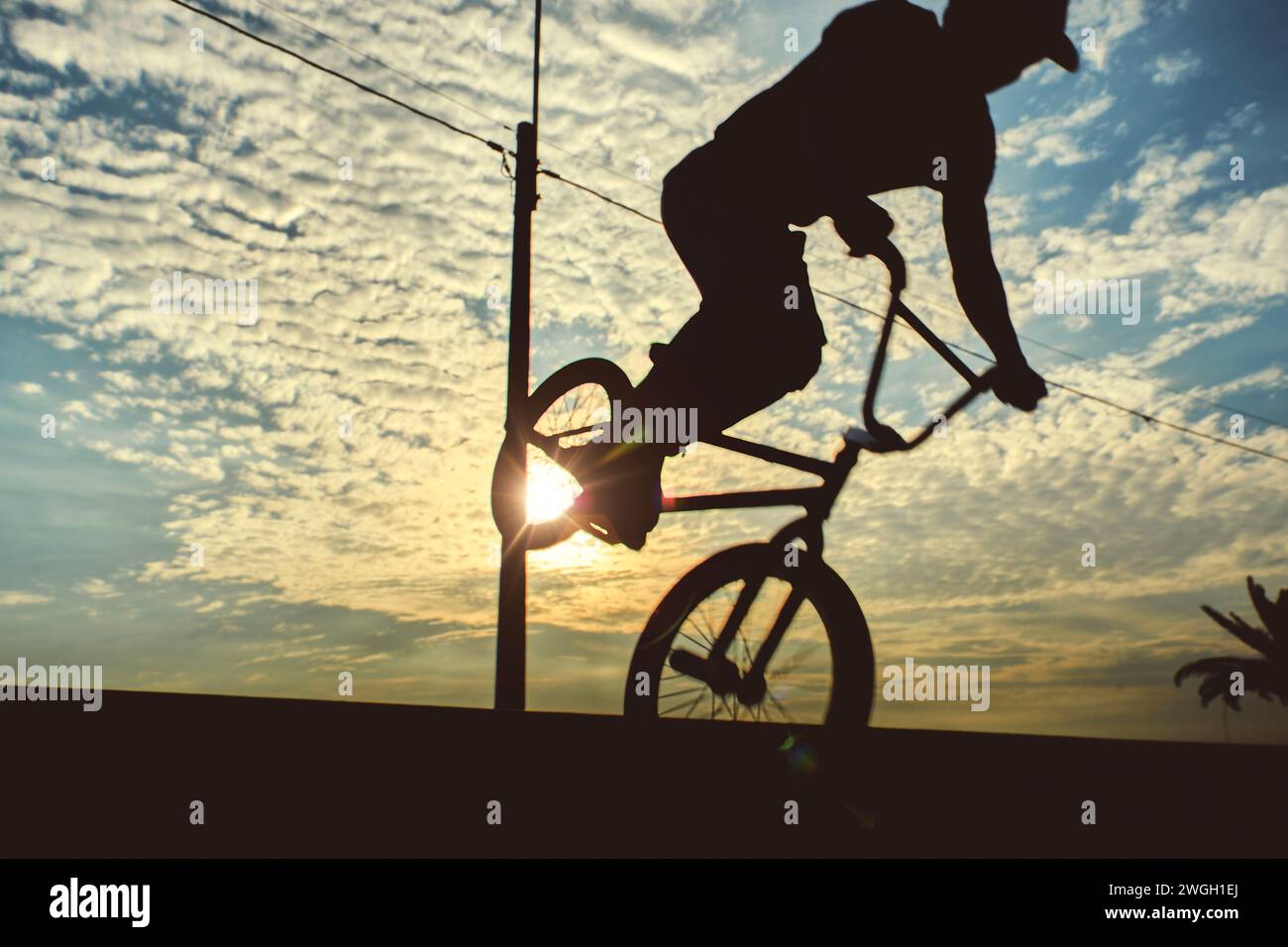 Silhouette unrecognizable Young man doing ramp jump stunt on bmx bicycle on sunset Stock Photo