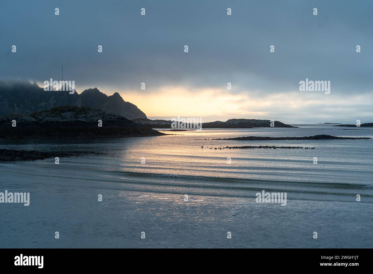 Sunbeams breaking through misty clouds over mountain range Stock Photo