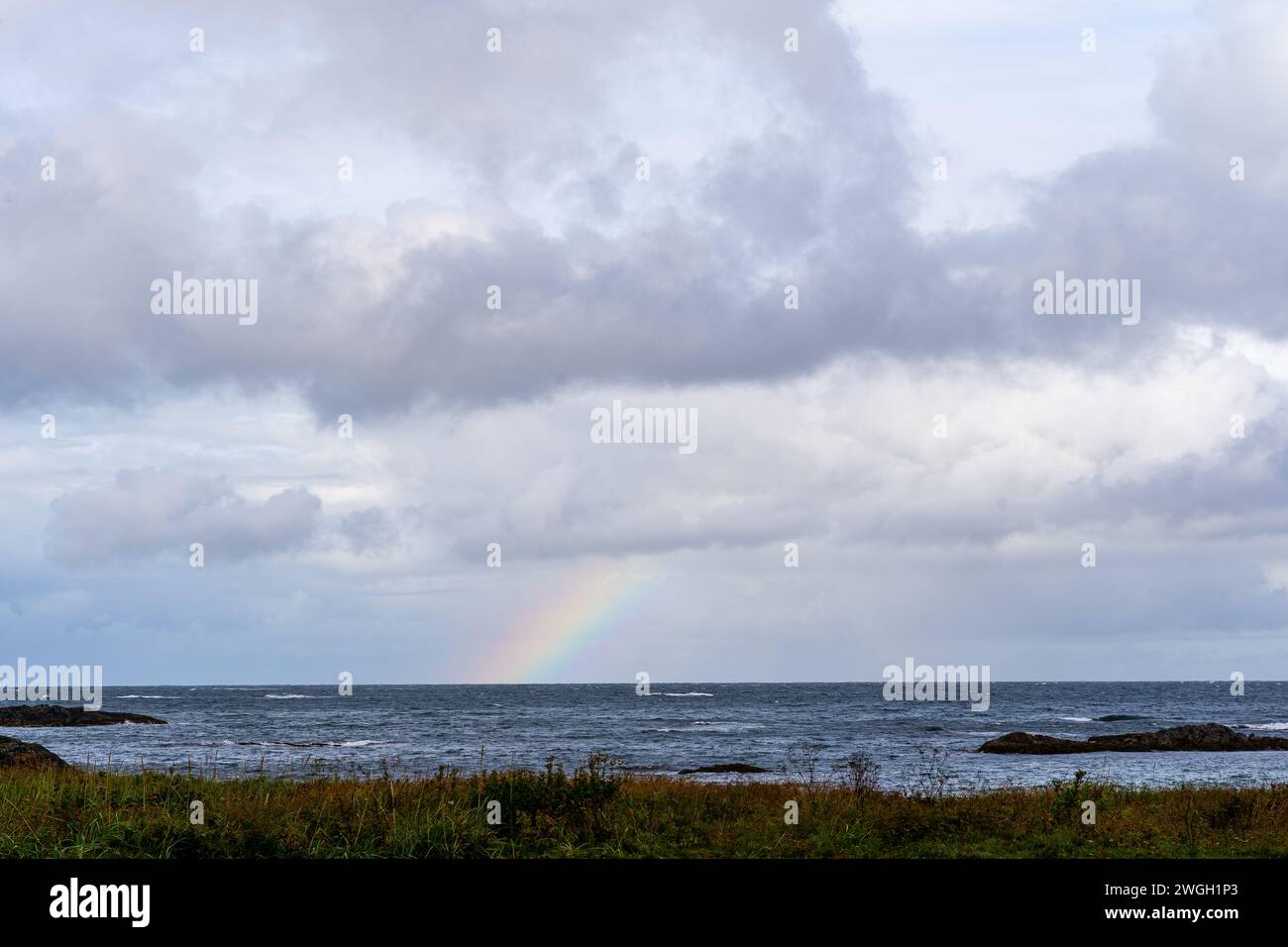 Rainbow above ocean on cloudy day Stock Photo