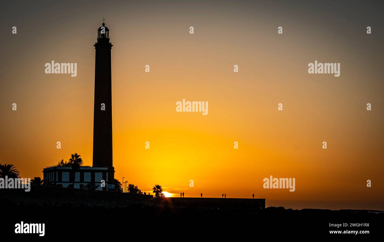Sunrise over Playa de Maspalomas, nice yellow orange sky, palms, calm ocean Stock Photo