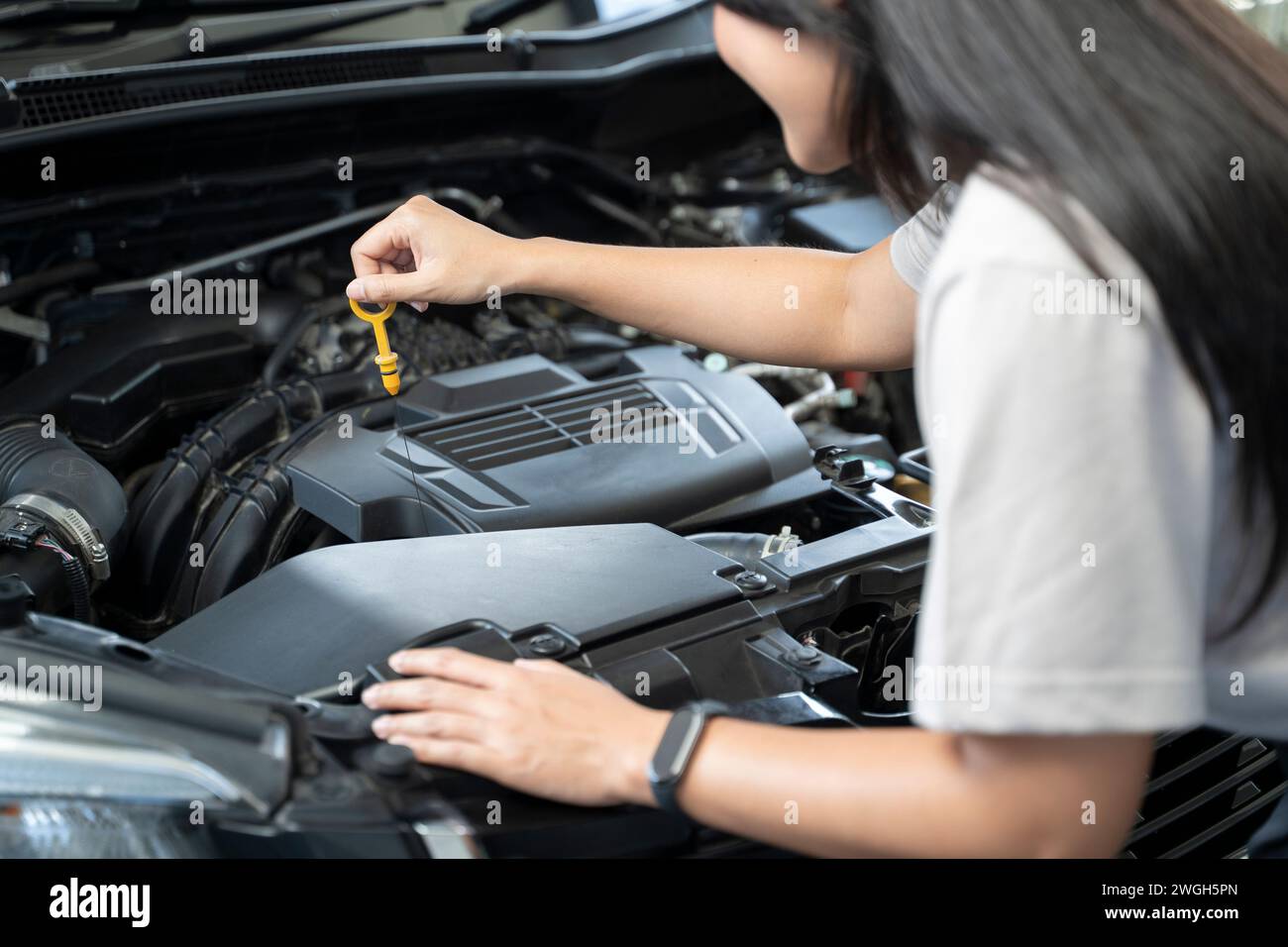 Woman standing next to a car with the hood up, checking the engine