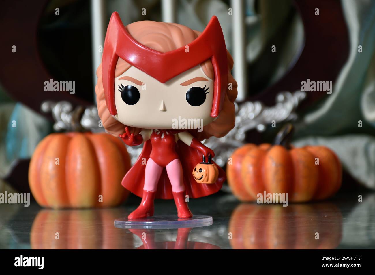 Funko Pop action figure of Marvel Avengers superhero Scarlet Witch in Halloween costume from tv series WandaVision. Pumpkins, decor, reflection. Stock Photo