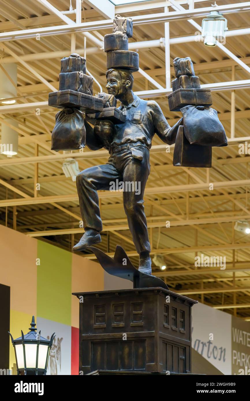 Sculpture or statue in a man likeness carrying a group of boxes and bags. The piece decorates a corridor in the Vaughan Mills shopping centre. Stock Photo