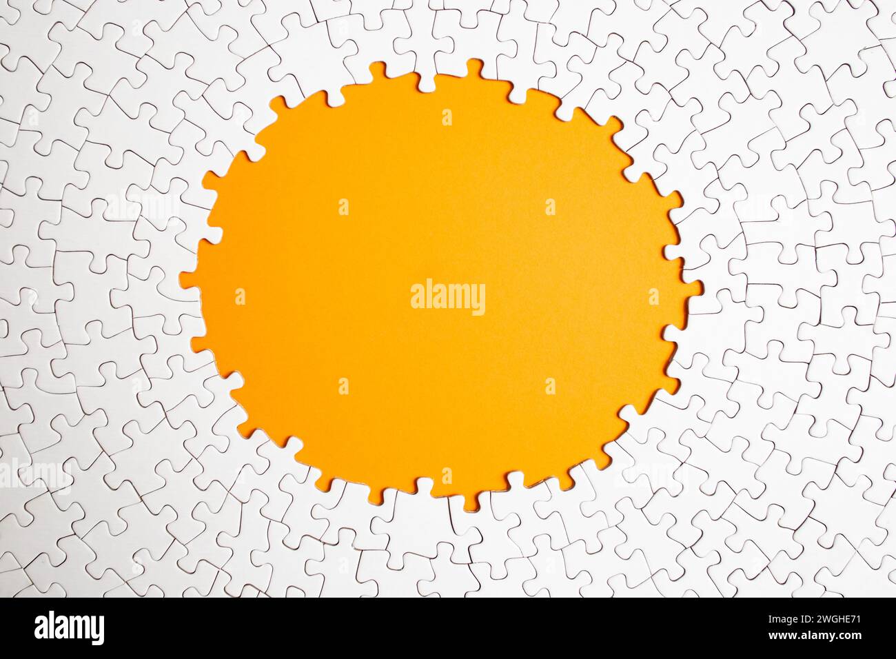 Plain white jigsaw puzzle  on yellow color background, oval shaped frame Stock Photo