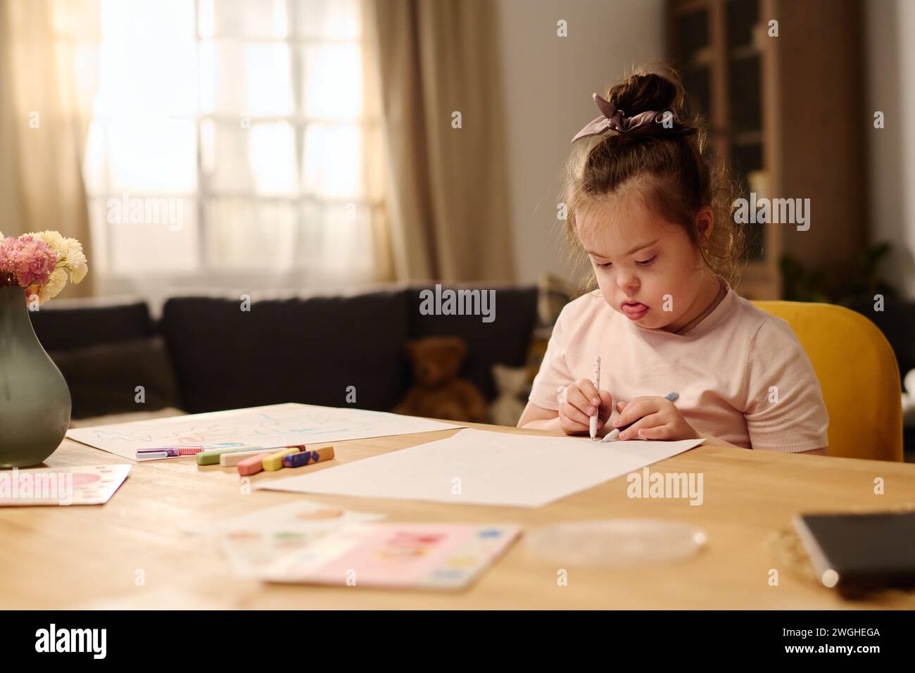 Adorable child with mental disability drawing with crayons on paper