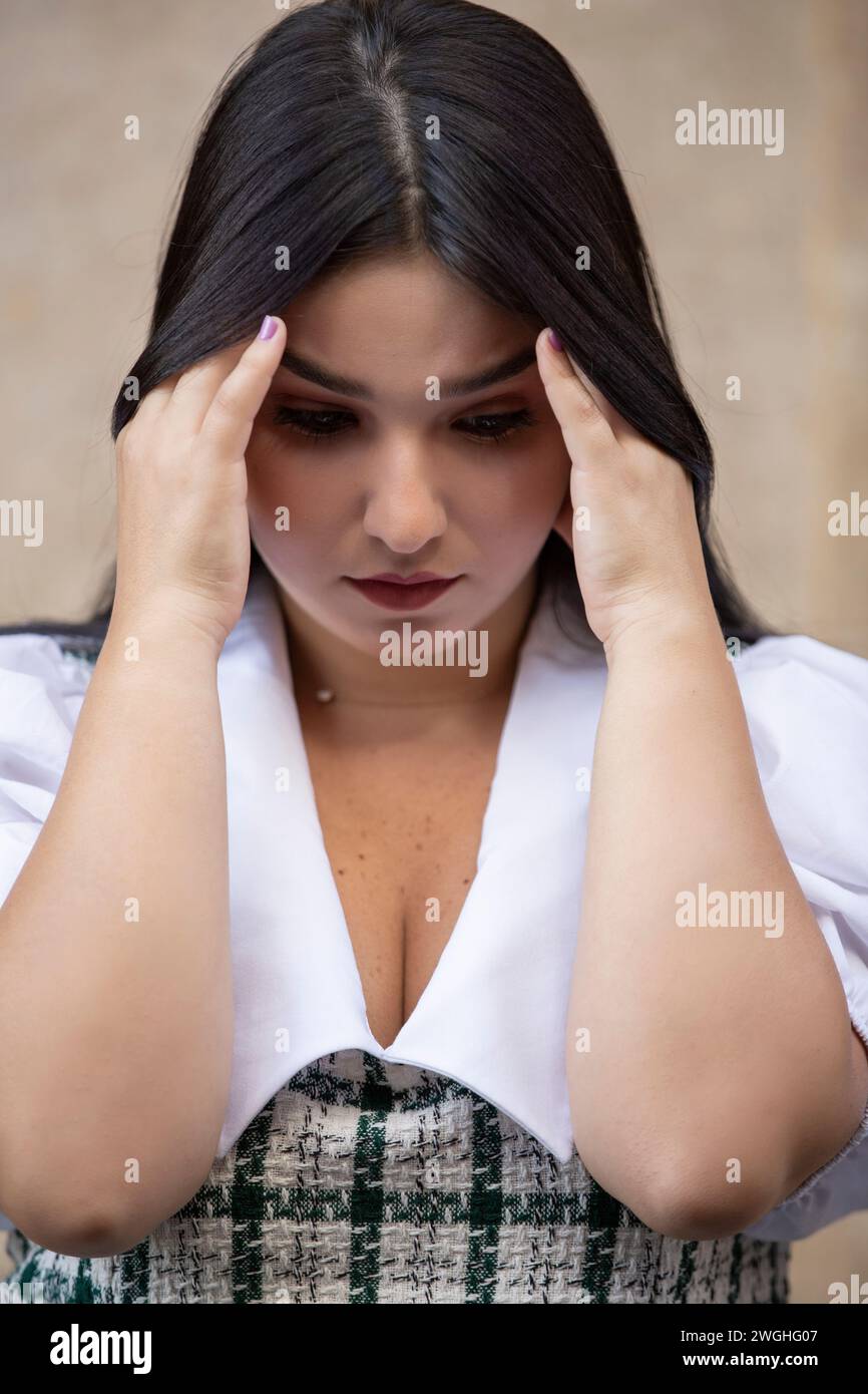 Tired young woman head in hands looking down Stock Photo