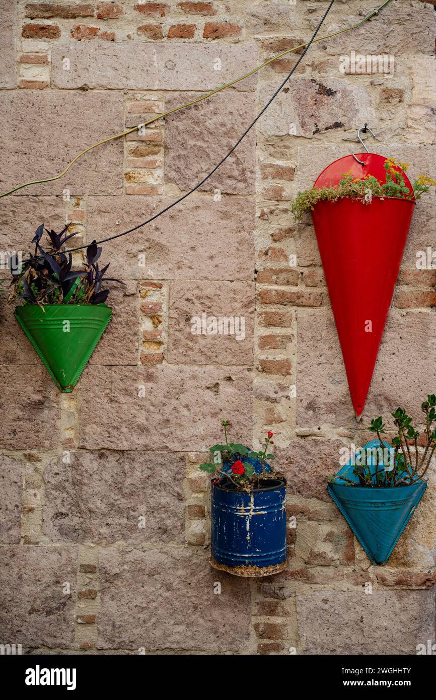Various color flower pots hanging on a wall. Stock Photo
