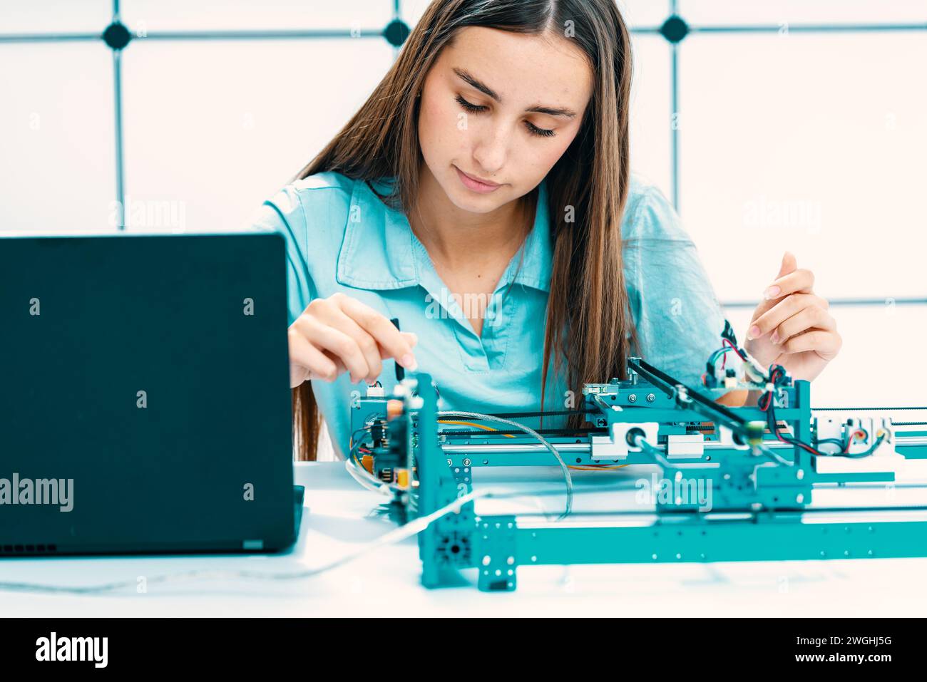 Front View of Woman Concentrating on Laptop, Working with Circuit Board in Electronics Industry Stock Photo