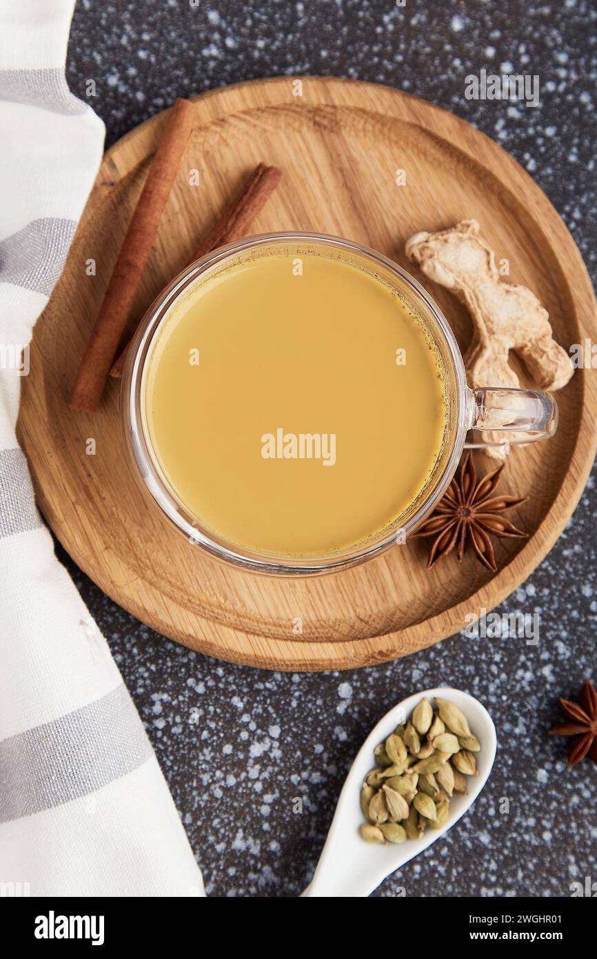 Indian spice cuisine. Cup of healthy masala tea, traditional drink with spices star anise, dried ginger, cinnamon, turmeric flat lay. Stock Photo