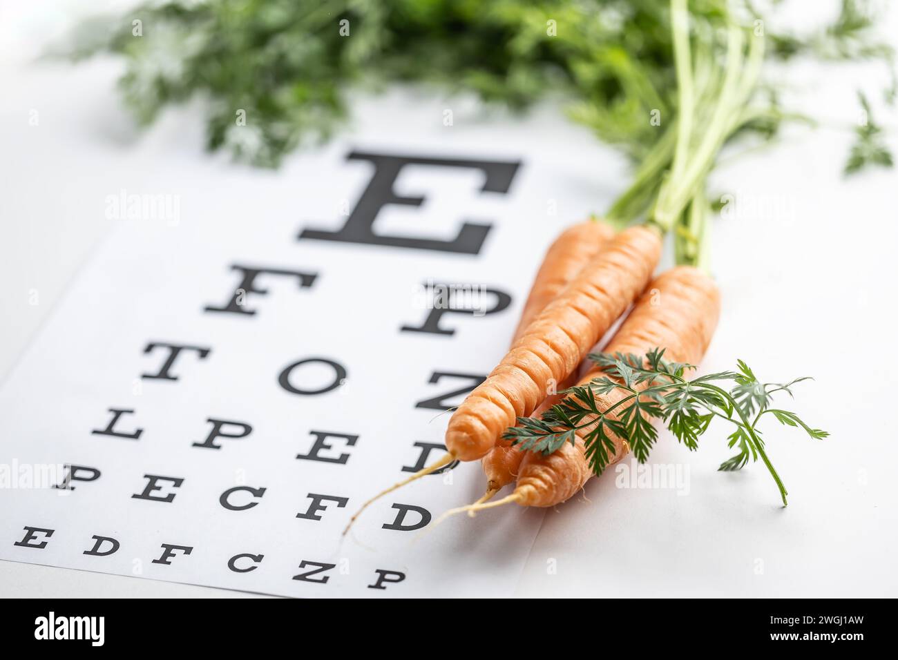 Fresh carrots as a source of vitamin A placed on the eye test chart. Stock Photo