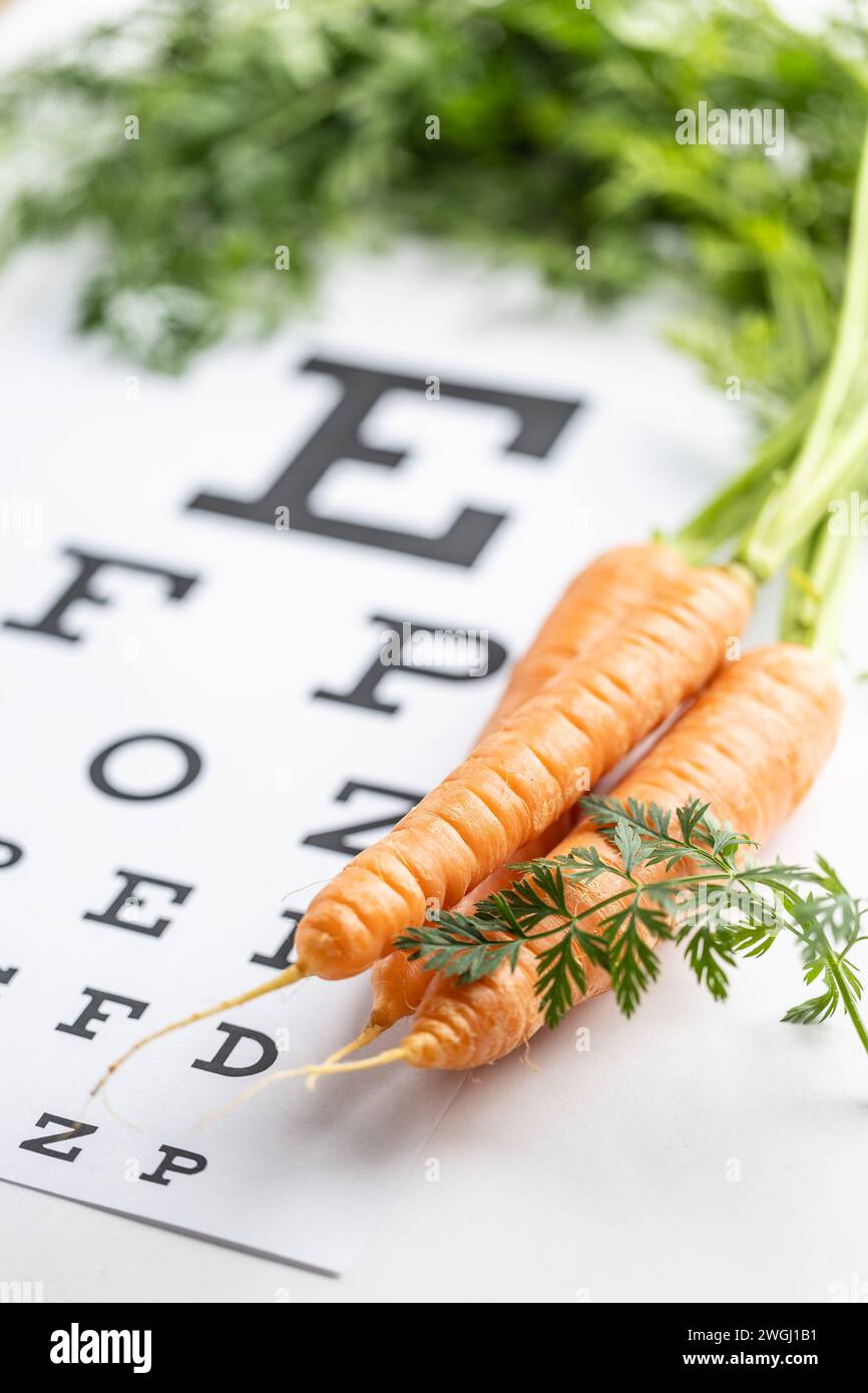 Fresh carrots as a source of vitamin A placed on the eye test chart. Stock Photo