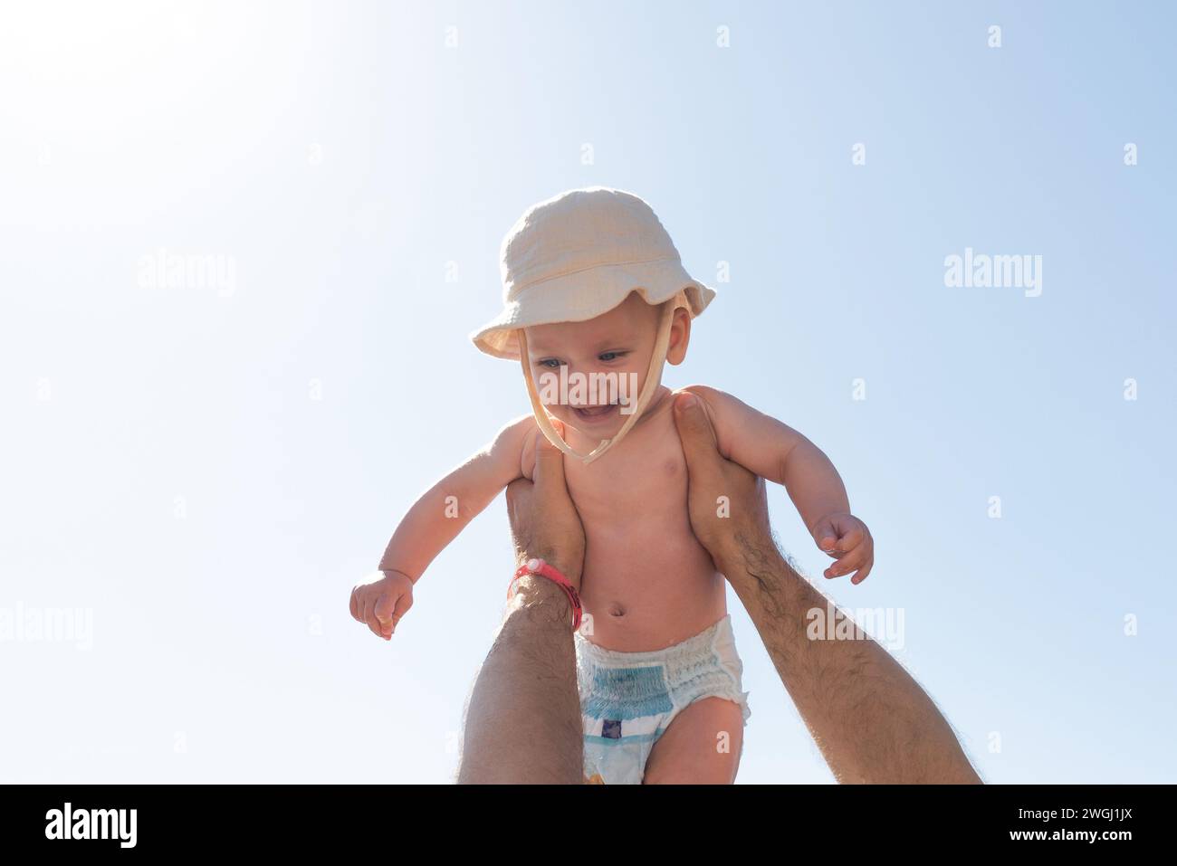 Sun-kissed moments of a father holding his infant high. Concept of paternal warmth and childhood glee Stock Photo