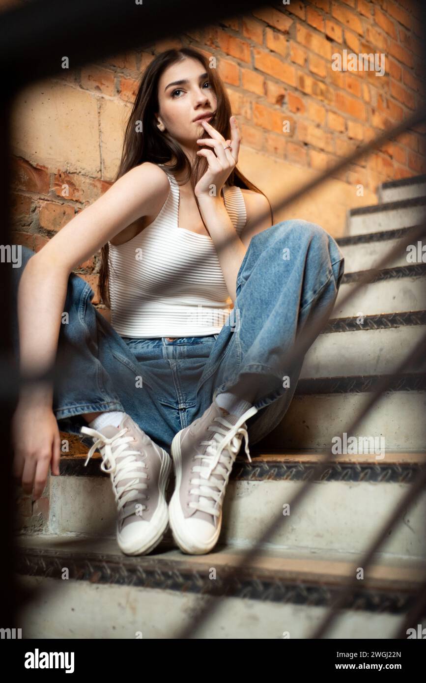 Young woman wearing casual denim jeans and white shirt posing in hall Stock Photo
