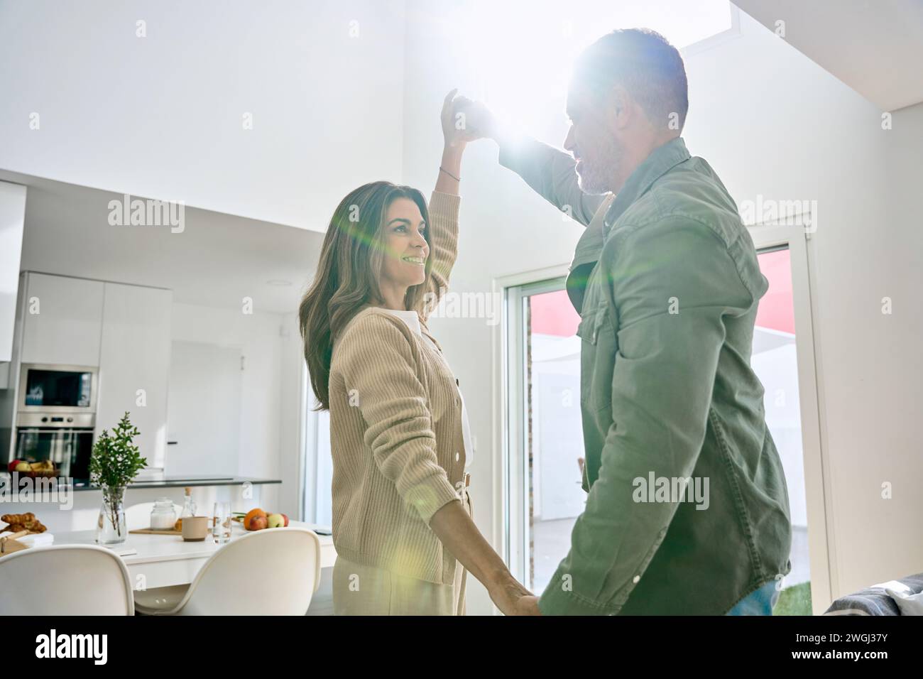Candid photo of happy smiling middle aged old couple dancing in kitchen. Stock Photo