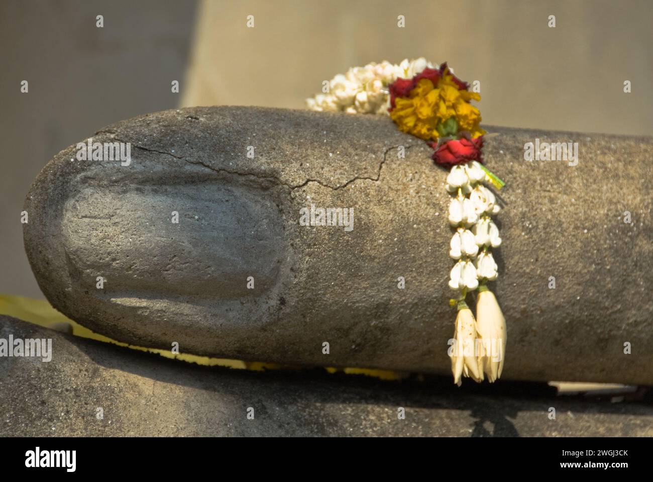 Elephant statue adorned with flowers against a wall Stock Photo
