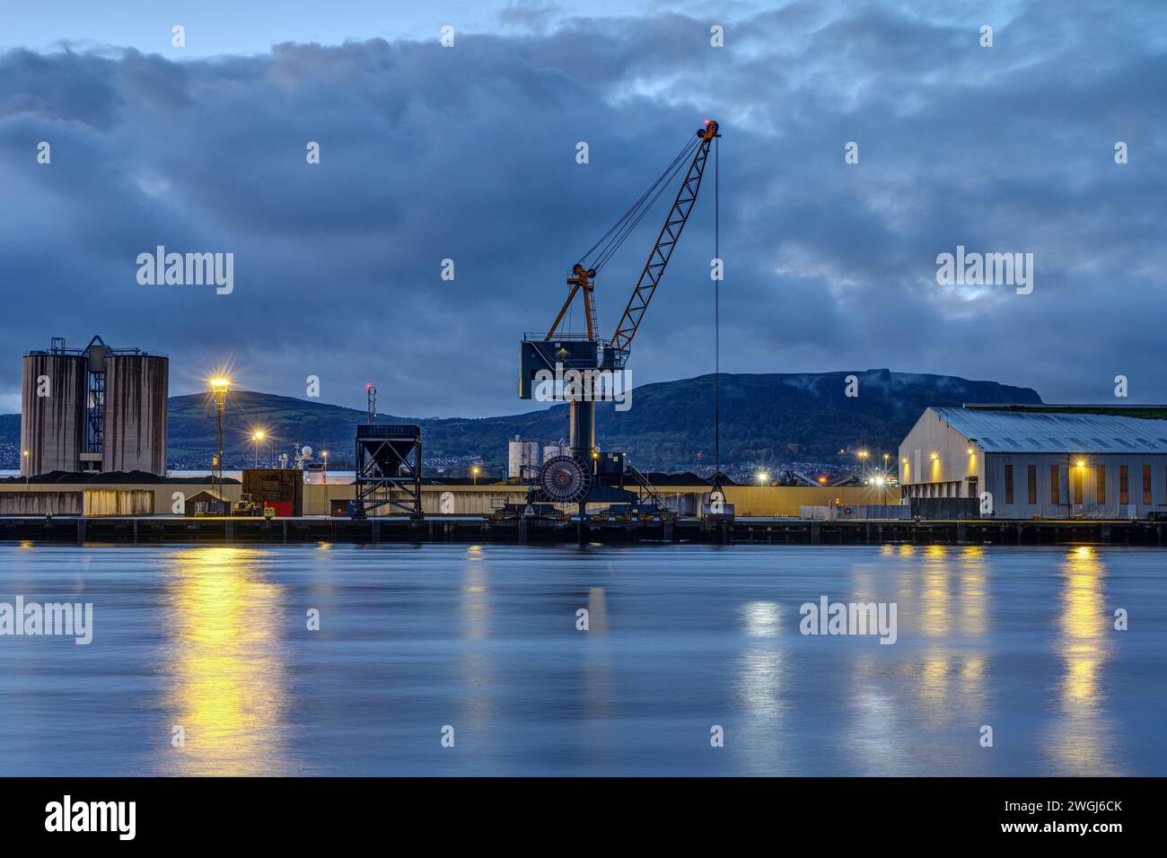 A loading crane and storehouses in the port of Belfast at twilight Stock Photo