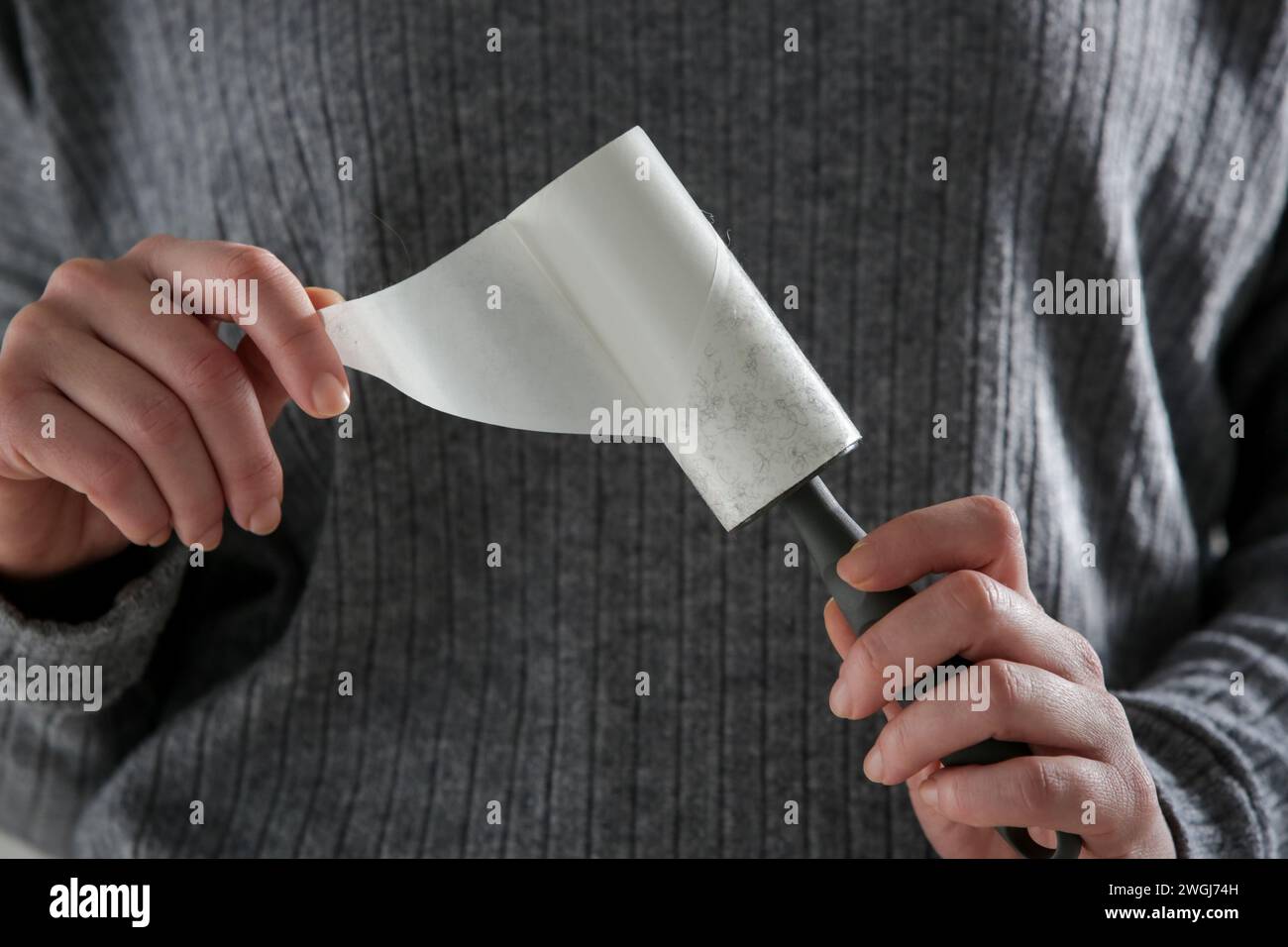 Hair remover roller. Woman using reusable clothes lint roller cleaner. Stock Photo