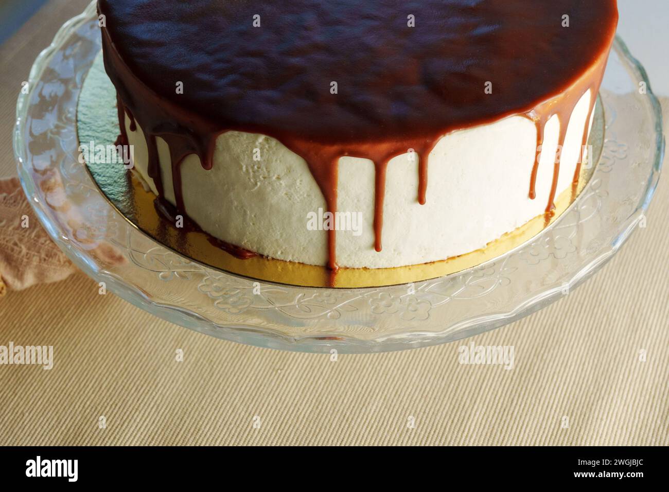 Classic cheesecake topped with a smooth chocolate ganache drips enticingly Stock Photo