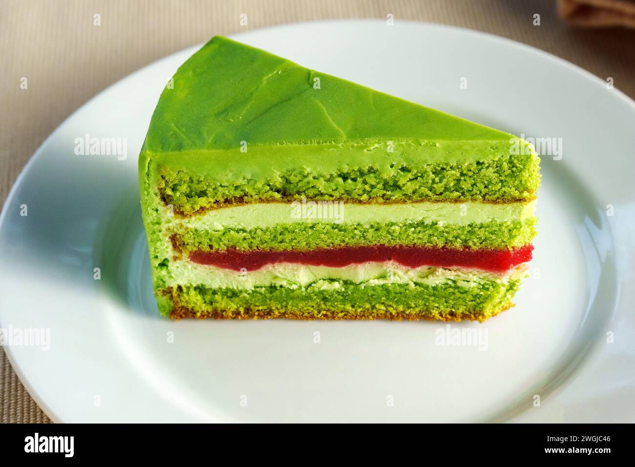Emerald Euphoria: A Sumptuous Slice of Verdant Green Cake on Delicate White Porcelain Stock Photo