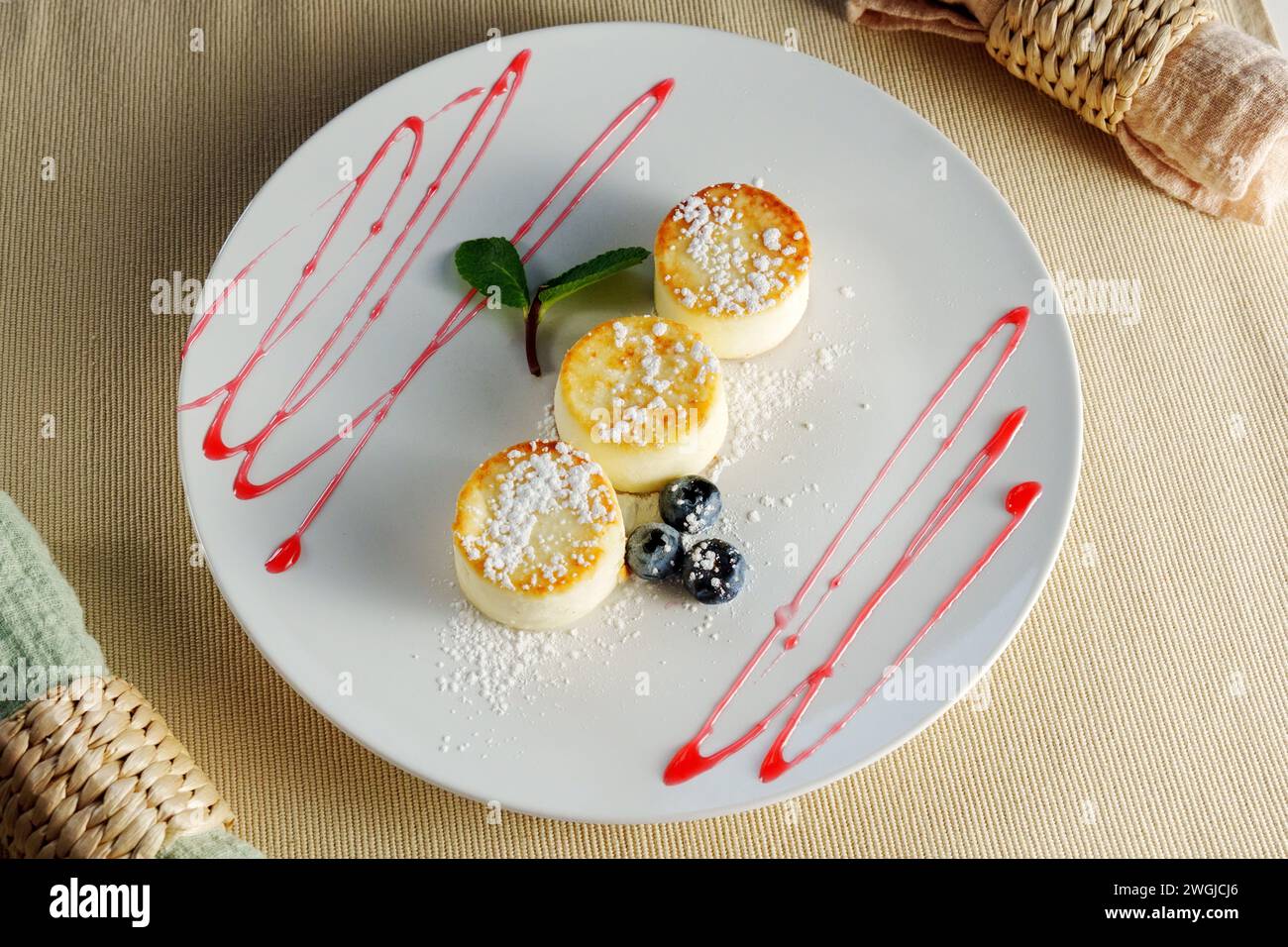 A white plate adorned with three delectable desserts rests gracefully atop a wooden table. Stock Photo