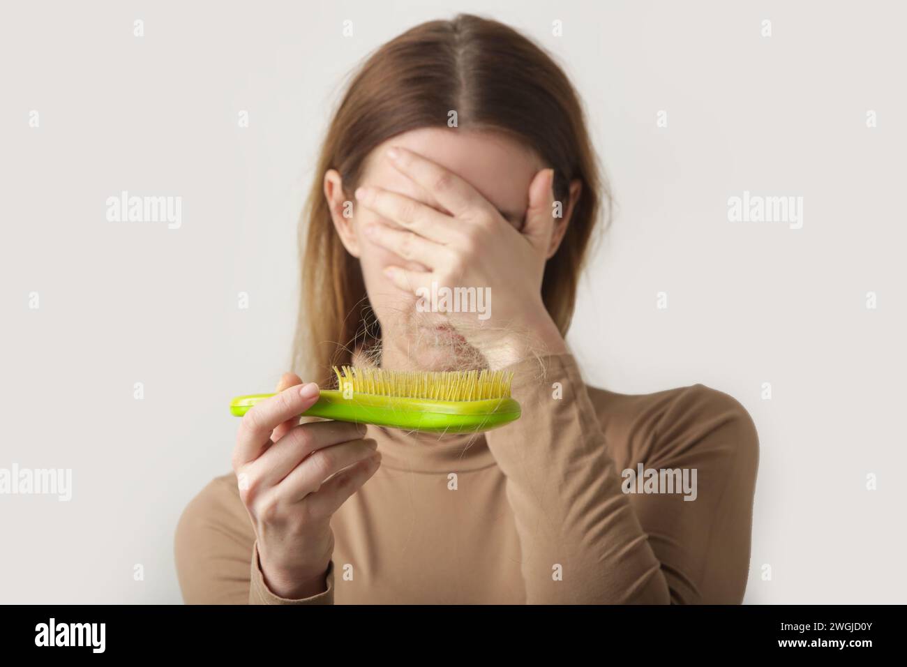 Woman holding detangler hair brush full of hair that has fallen out, loss hair problem Stock Photo