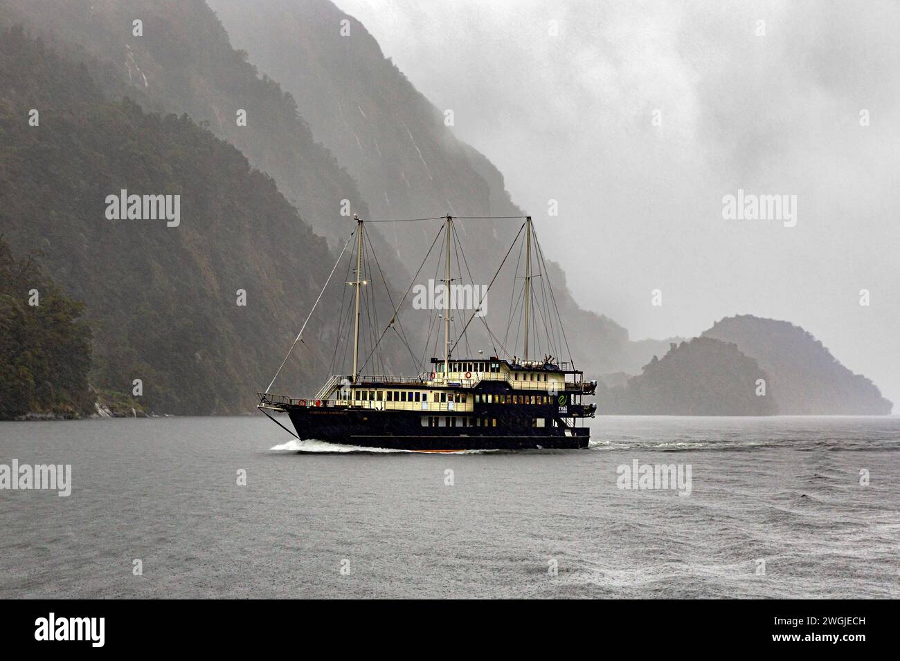Tourist cruise ship making way on a rainy day in Doubtful Sound / Patea, Fiordland /Te Rua-o-te-Moko, New Zealand / Aotearoa, South Island /Te Waipoun Stock Photo