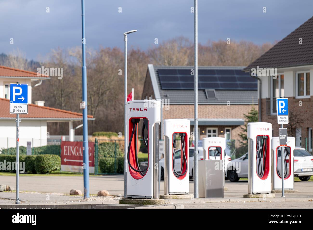 , Energie, Deutschland, Baden-Württemberg, Hirschberg an der Bergstraße, 05.02.2024,  Tesla-Ladestationen in Reihe mit markanten roten Kabeln. Stock Photo