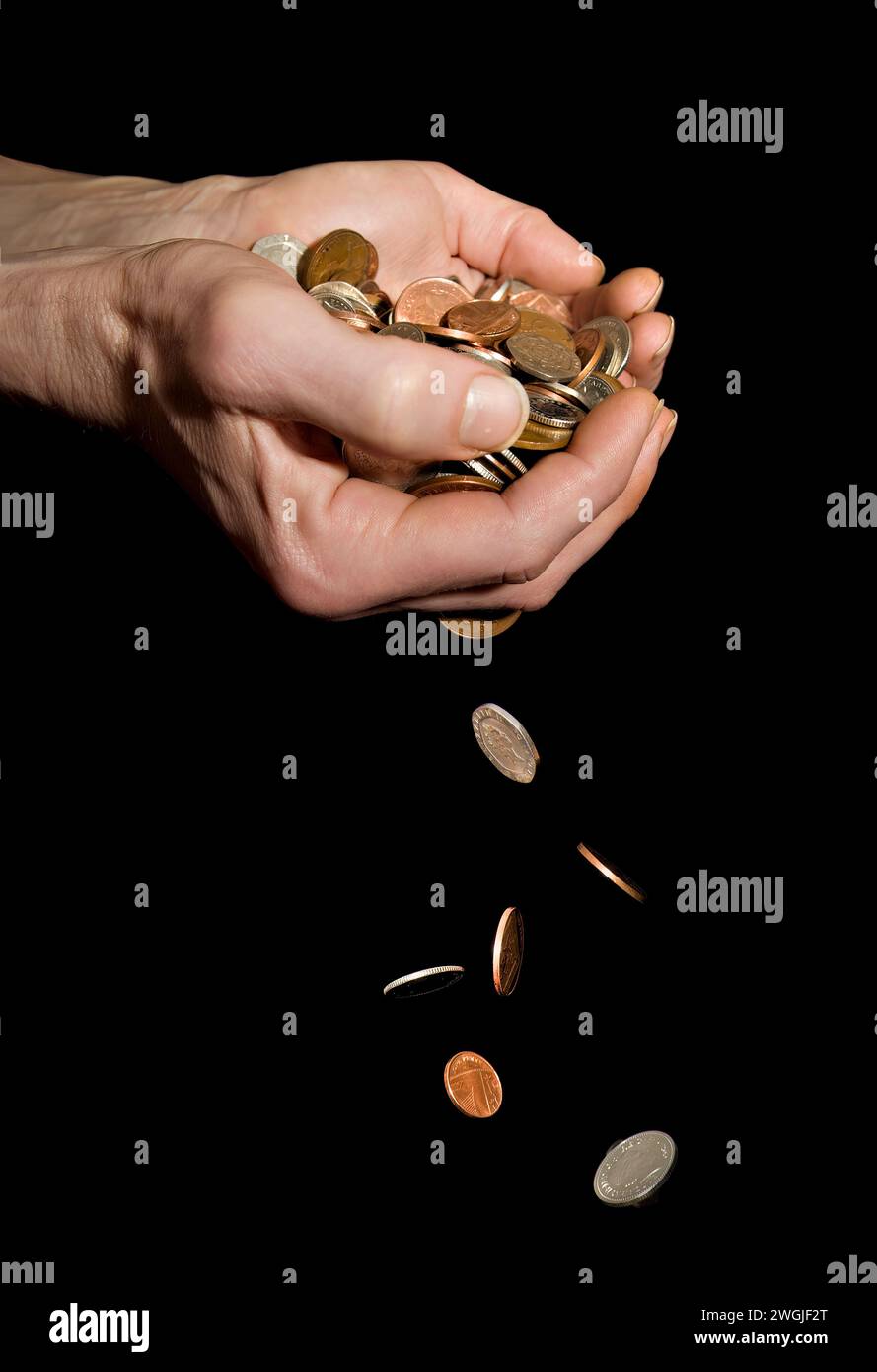 Caucasian male (42 yrs old) hands with money falling depicting the concept of ‘money slipping through hands’ or ‘too much money to hold’ Stock Photo