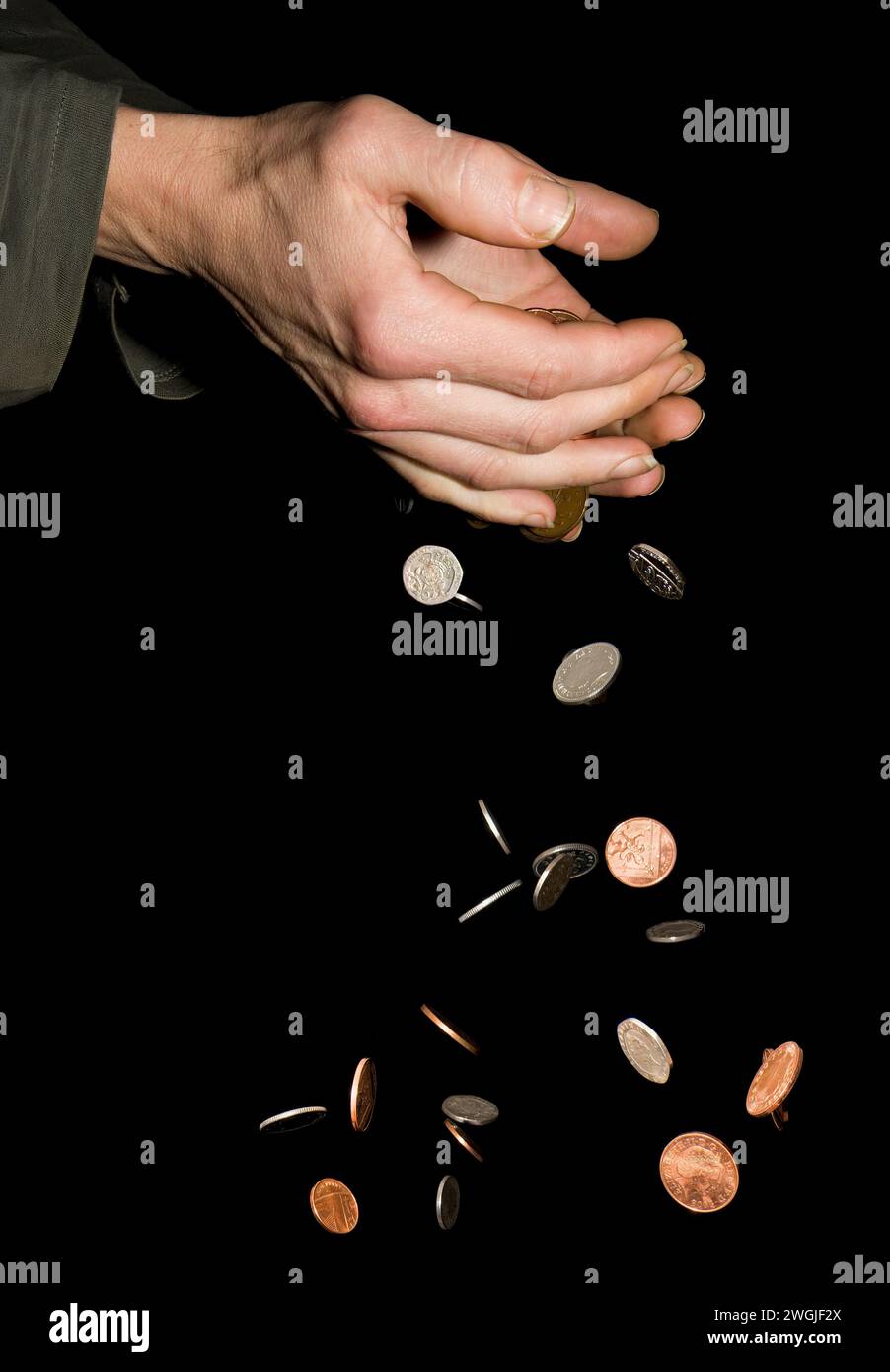 Caucasian male (42 yrs old) hands with money falling depicting the concept of ‘money slipping through hands’ or ‘too much money to hold’ Stock Photo