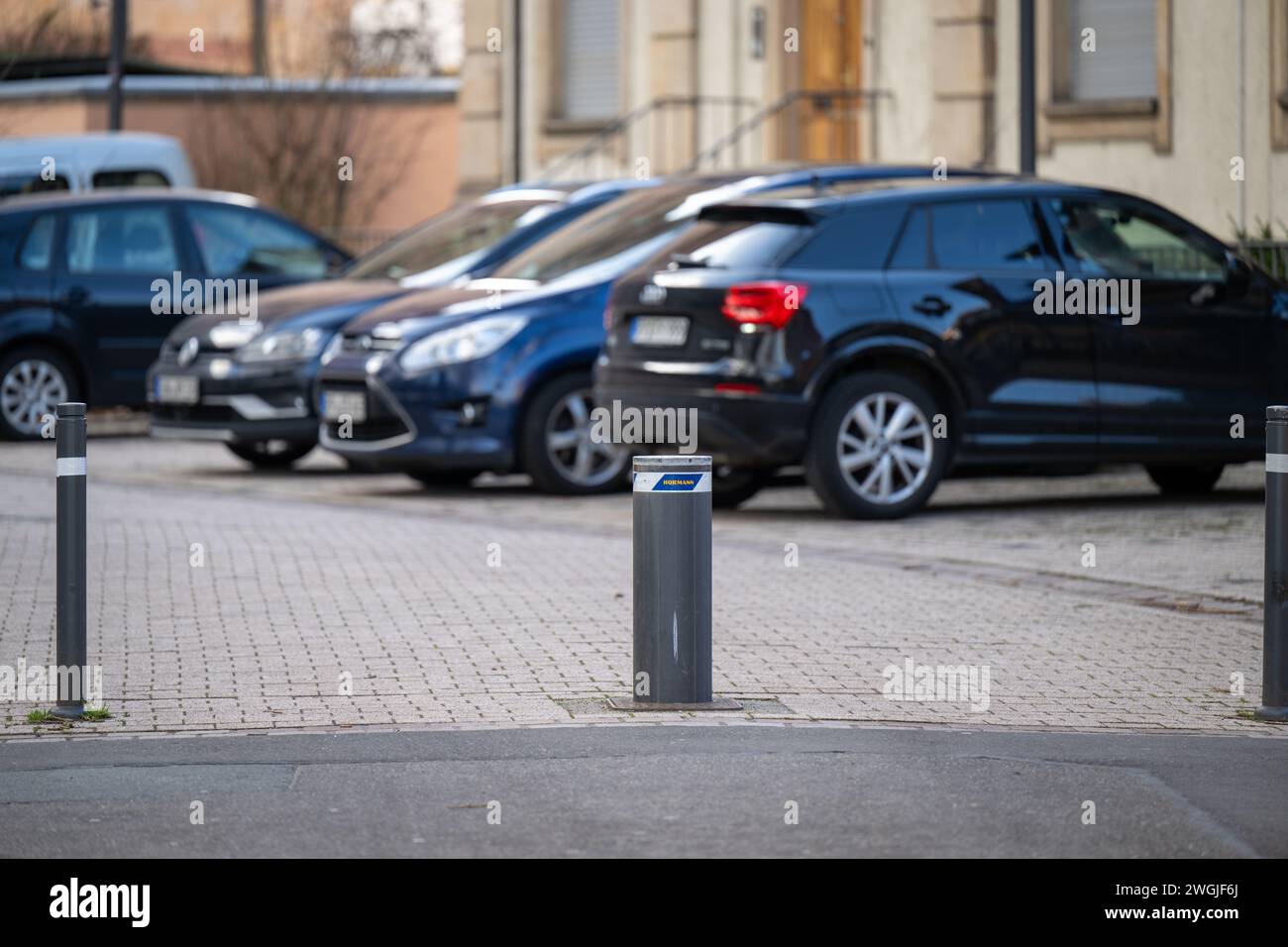, Alltag, Deutschland, Rheinland-Pfalz, Speyer, 05.02.2024,  Parkende Autos auf gepflastertem Platz, Vordergrund zeigt einen Poller der sich bei Bedar Stock Photo