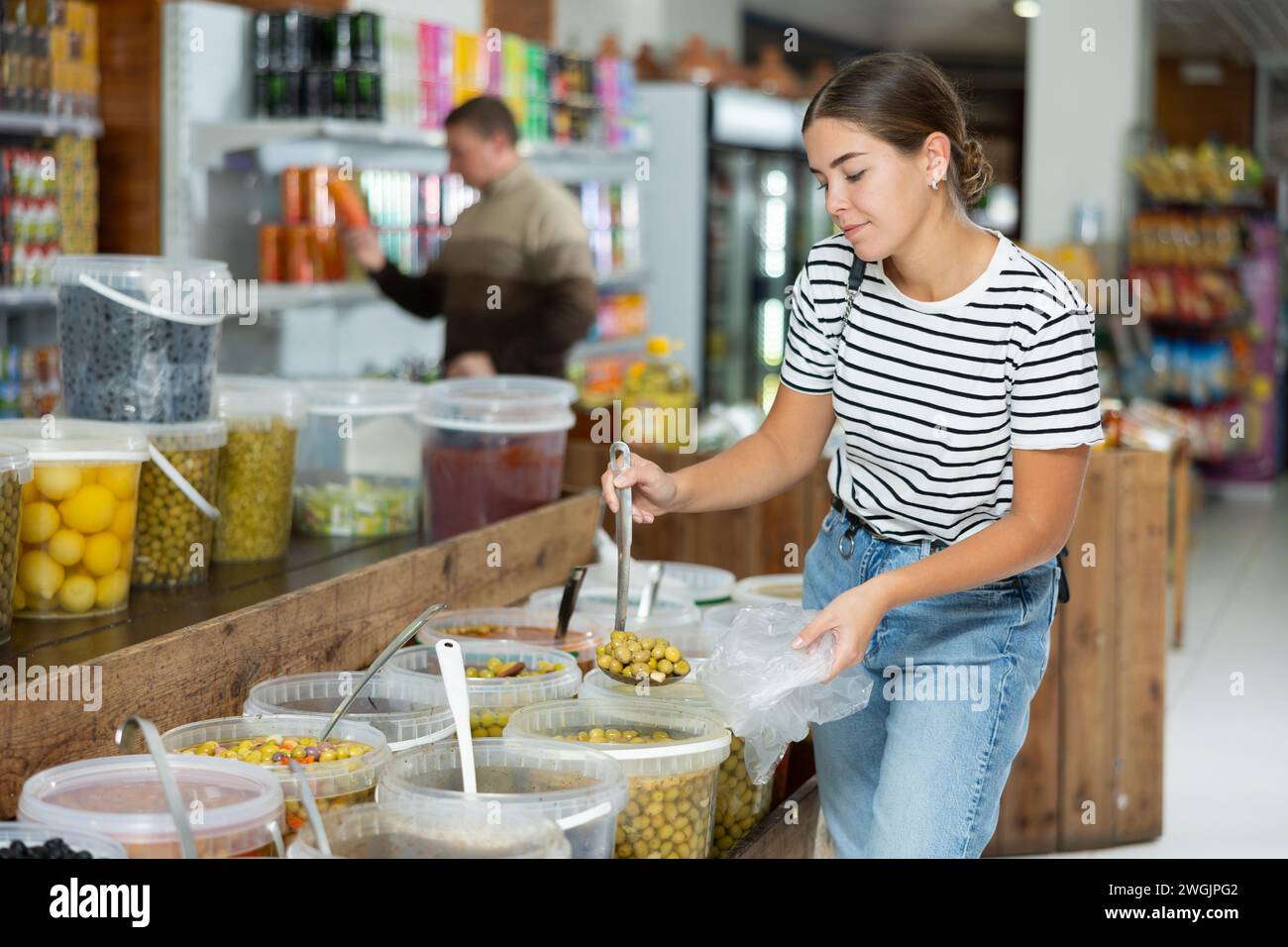 Female shopper scooping pickled olives in grocery store Stock Photo Alamy