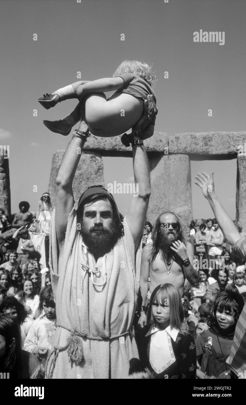 Bev Richardson also know as Pagan Bev holds a young boy who has just been baptised up for the crowd to celebrate. His sister stands next to Bec. Stonehenge Free Festival at the summer solstice, Wiltshire, England June 21st 1979.  1970s UK HOMER SYKES Stock Photo