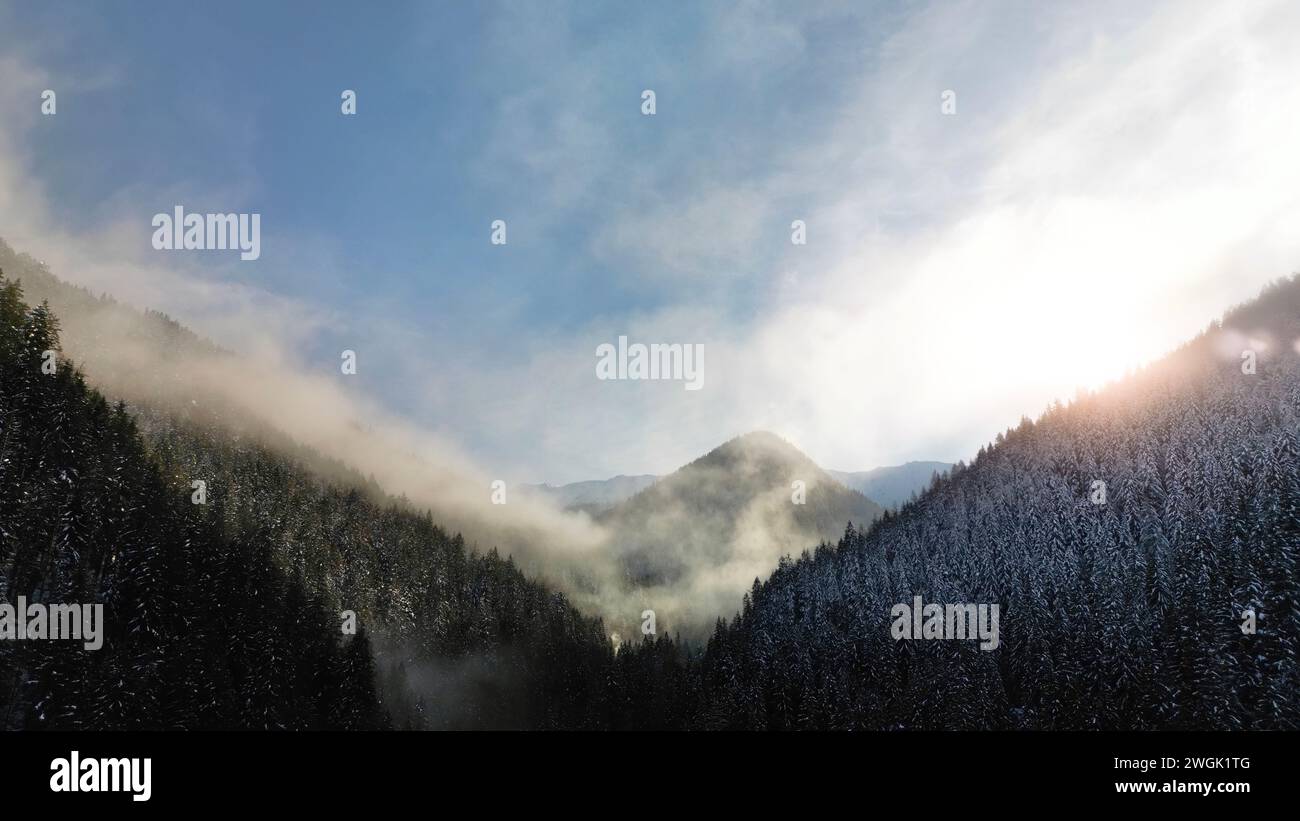 Aerial view of foggy winter forest and sunrise in Low Tatras mountains of Slovakia. Cold morning scenic panoramic snowscape with pine trees and fog on Stock Photo