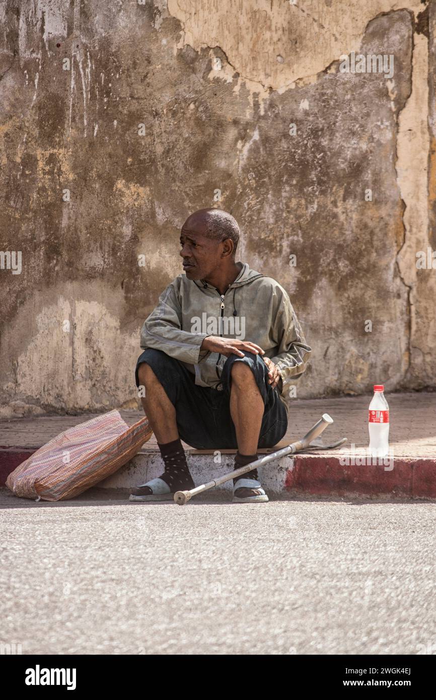 A man seated on the streets of Tangier, a Moroccan port on the Strait of Gibraltar, has been a strategic gateway between Africa and Europe since Phoenician times. Its whitewashed hillside medina is home to the Dar el Makhzen, a palace of the sultans that's now a museum of Moroccan artifacts. The American Legation Museum, also in the medina, documents early diplomatic relations between the U.S. and Morocco in an 1821 Moorish-style former consulate. Morocco. Stock Photo