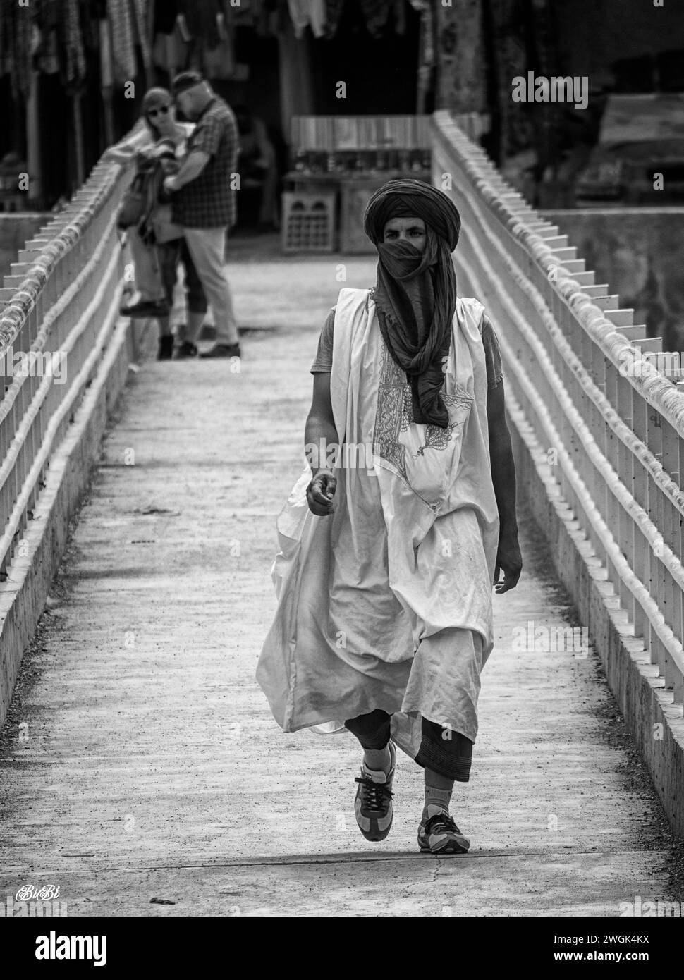 A local arab man in traditional dress crossing a bridge in Merzouga, a small Moroccan town in the Sahara Desert, near the Algerian border. It’s known as a gateway to Erg Chebbi, a huge expanse of sand dunes north of town. West of Merzouga, Dayet Srji is a seasonal salt lake that’s often dry in summer. When full, it attracts a wide range of migratory and desert birds, including desert warblers, Egyptian nightjars and, occasionally, flamingos. Morocco. Stock Photo