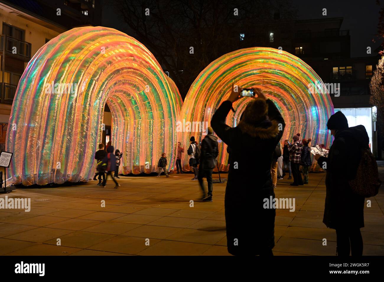 Series of giant inflatable arches at night, “Elysian” by Atelier Sisu part of Bristol Light Festival 2-11 Feb 2024 with visitors taking photographs Stock Photo