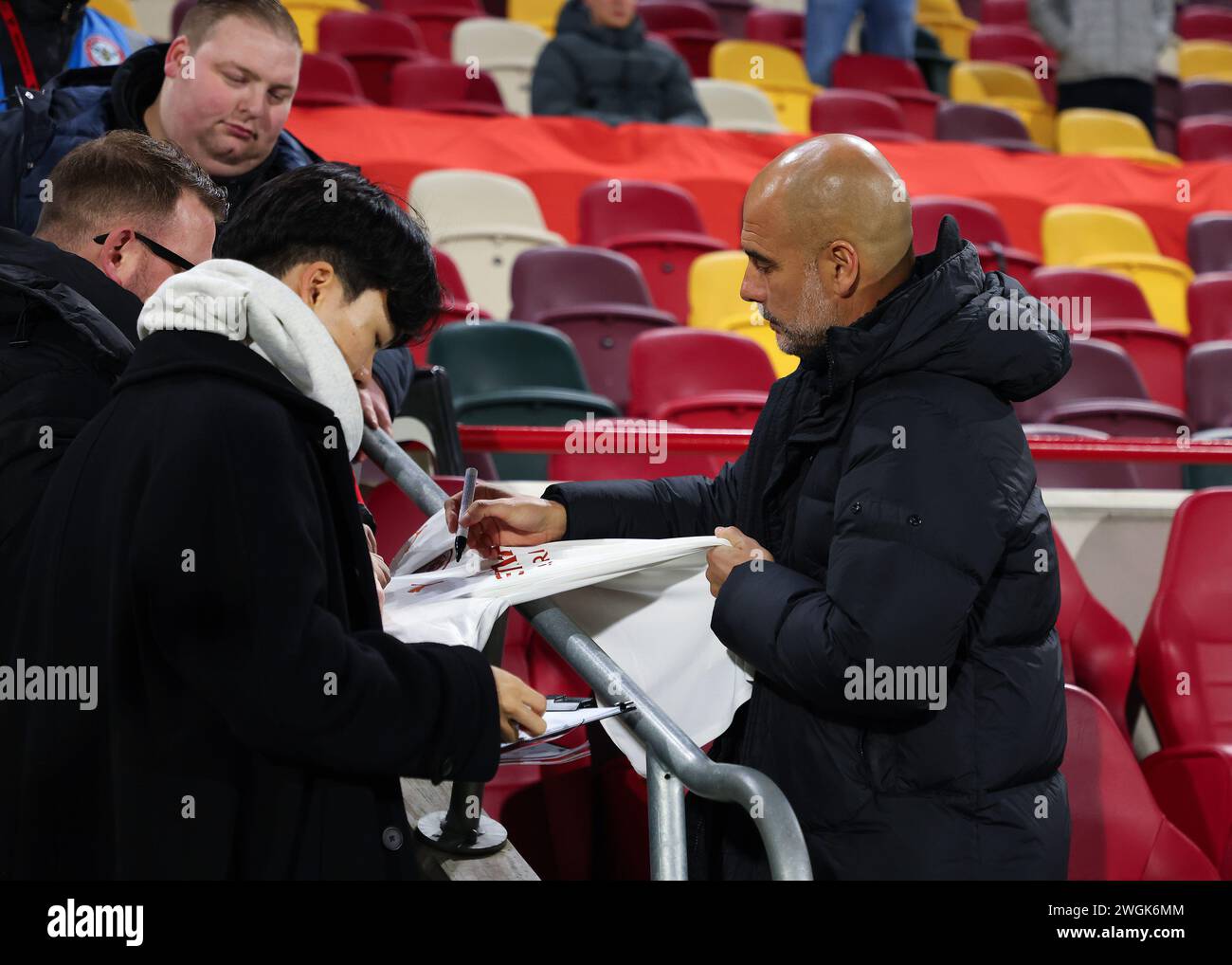 Brentford, London, UK. 5th February 2024; Gtech Community Stadium, Brentford, London, England; Premier League Football, Brentford versus Manchester City; Manchester City manager Pep Guardiola signing a Manchester City away shirt from the dugout before kick off Credit: Action Plus Sports Images/Alamy Live News Stock Photo