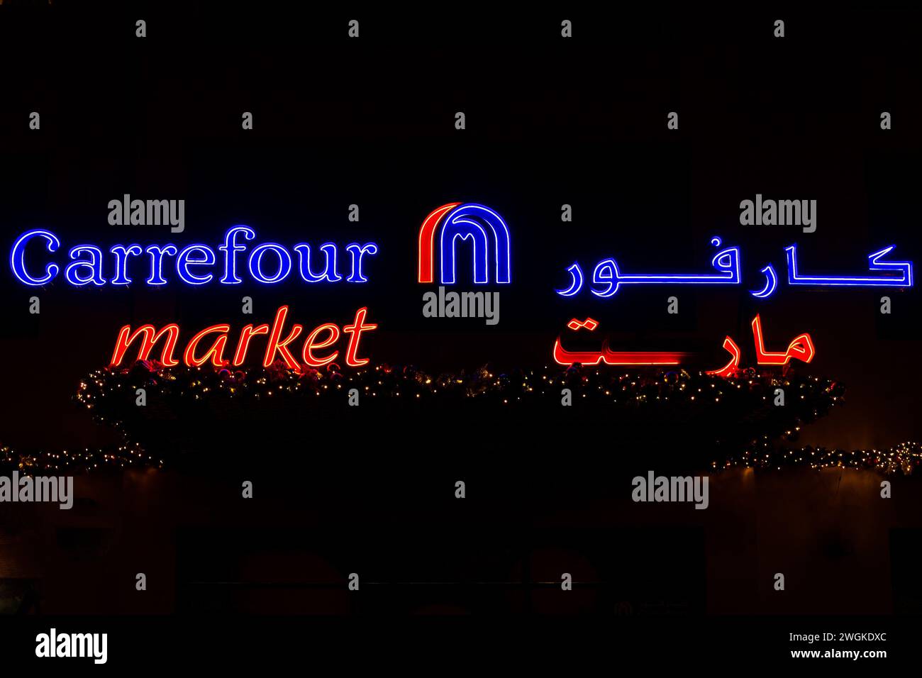 Dubai, UAE, 10.10.21. Carrefour market illuminated logo with Arabic brand name and Christmas lights decorations against black background, Dubai, UAE Stock Photo