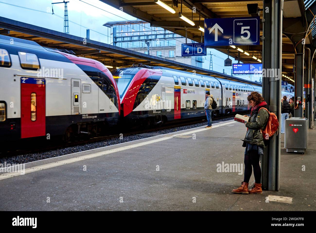 Geneva city in Switzerland Gare de Genève train station passenger reading a book waiting for her train Stock Photo
